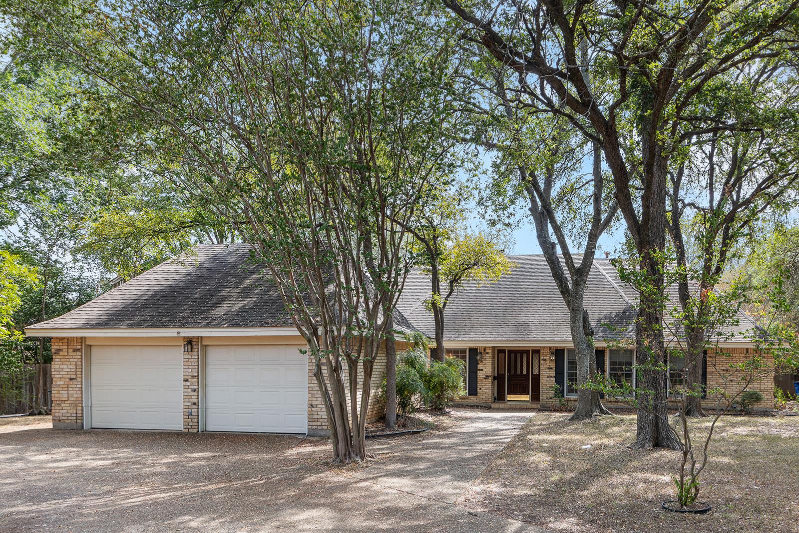 Mature trees shade a classic brick exterior featu