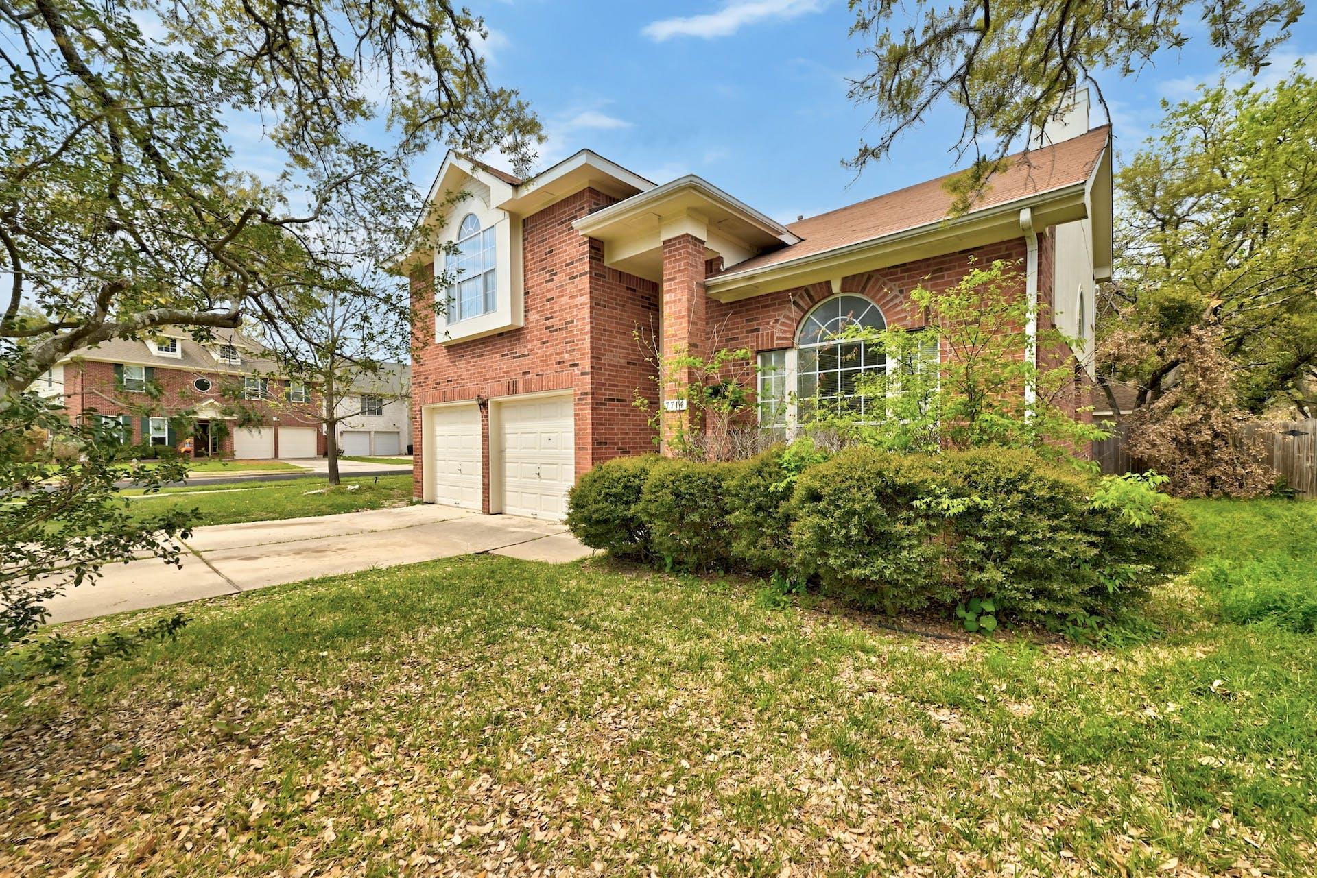 Mature trees shade a classic brick exterior featu