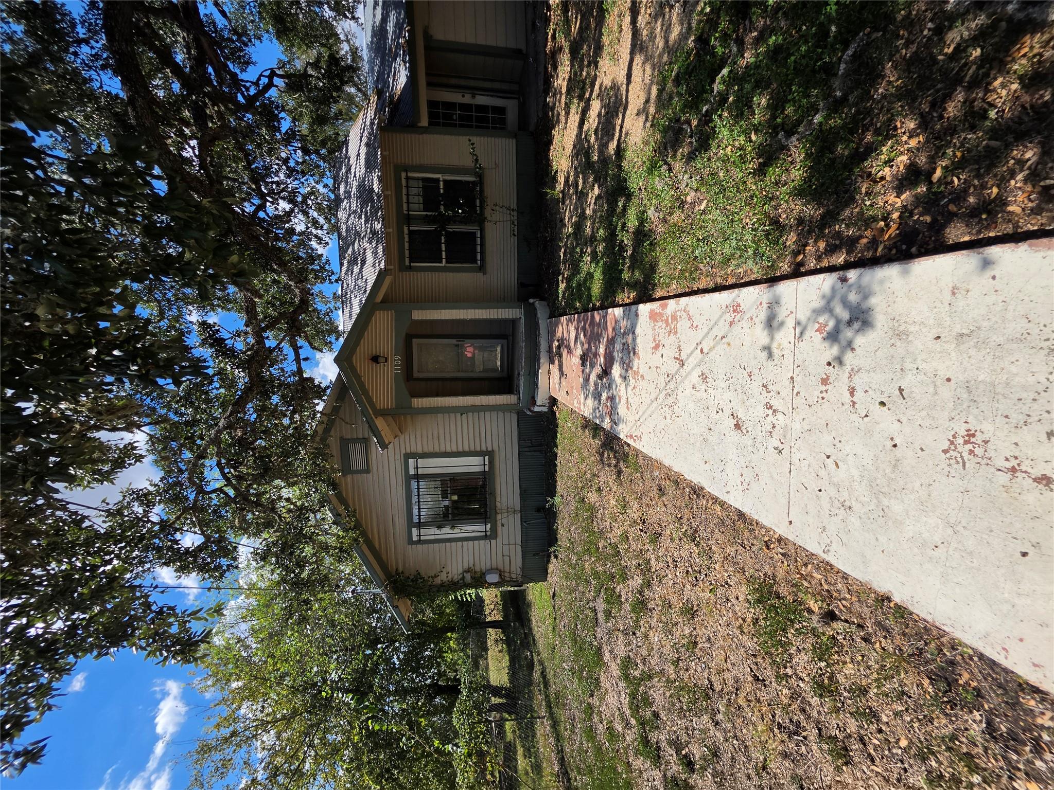 Mature shade trees frame a concrete path leading 