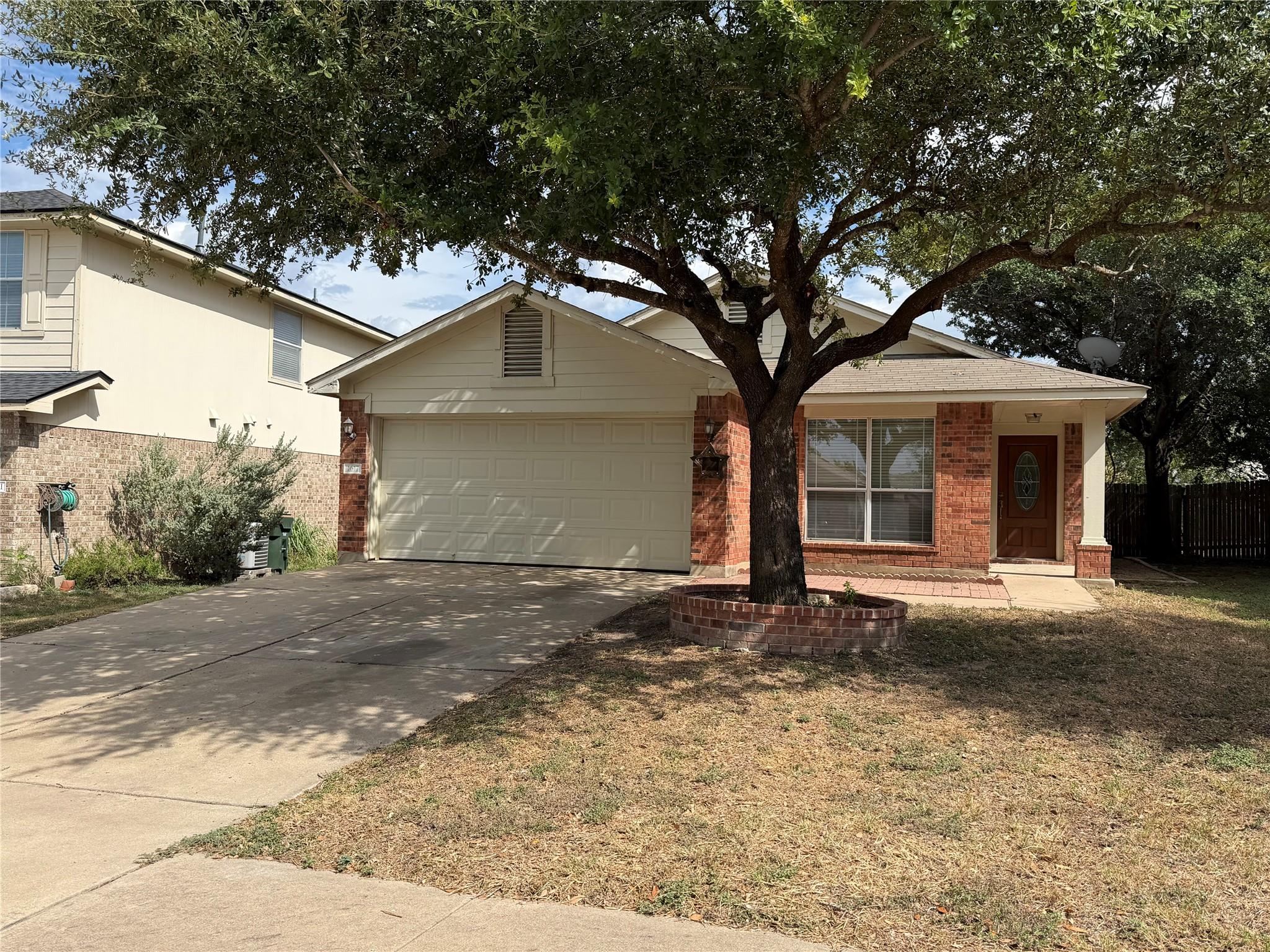 Classic brick accents and a mature shade tree fra