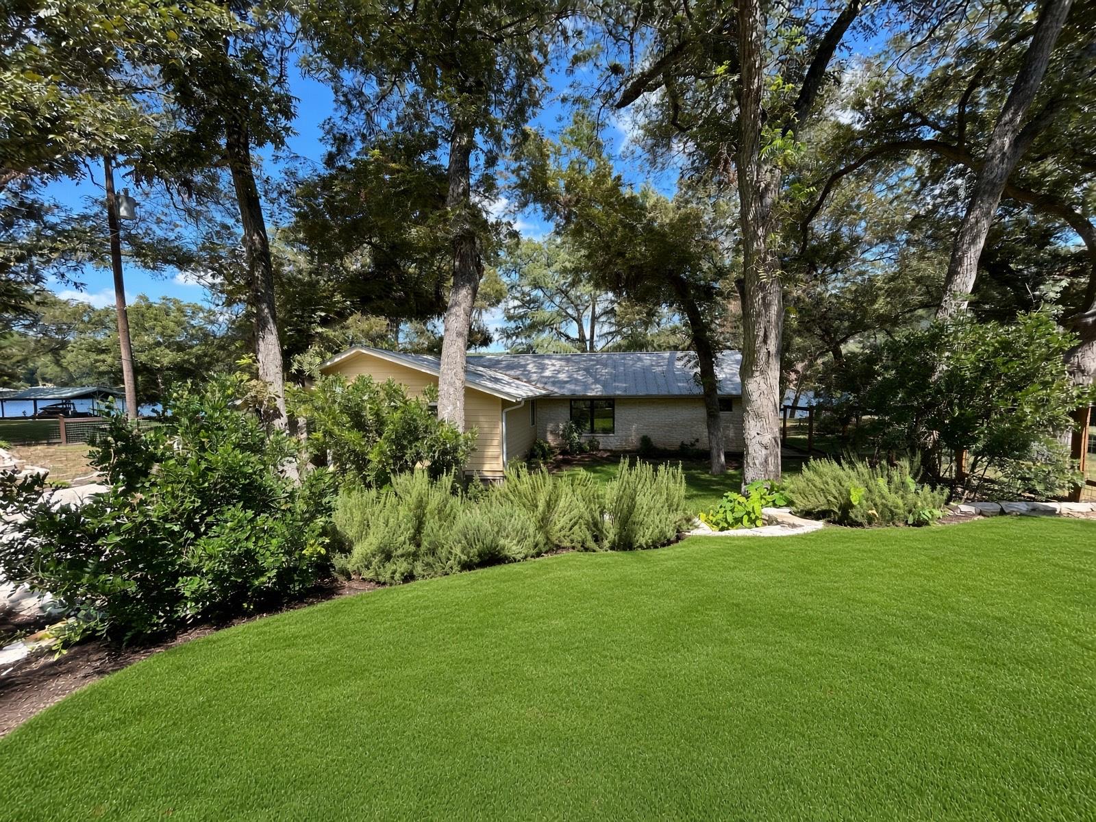 Mature trees shade a manicured lawn leading towar