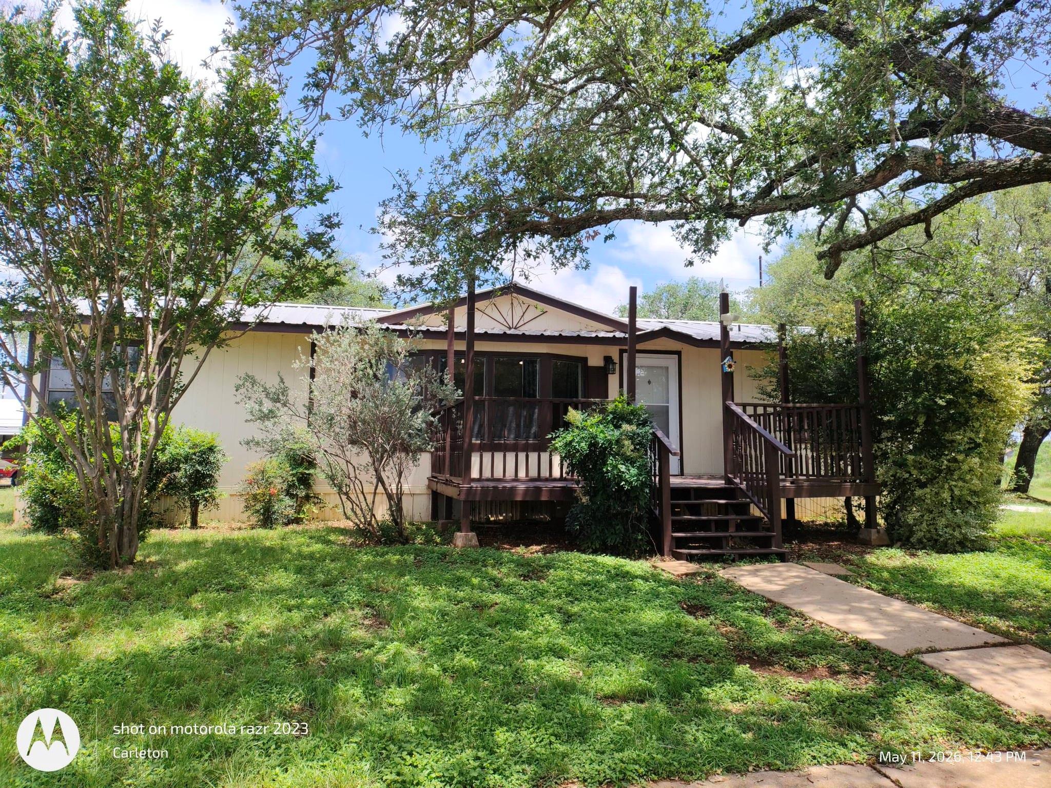 Mature trees shade the front deck and entrance of