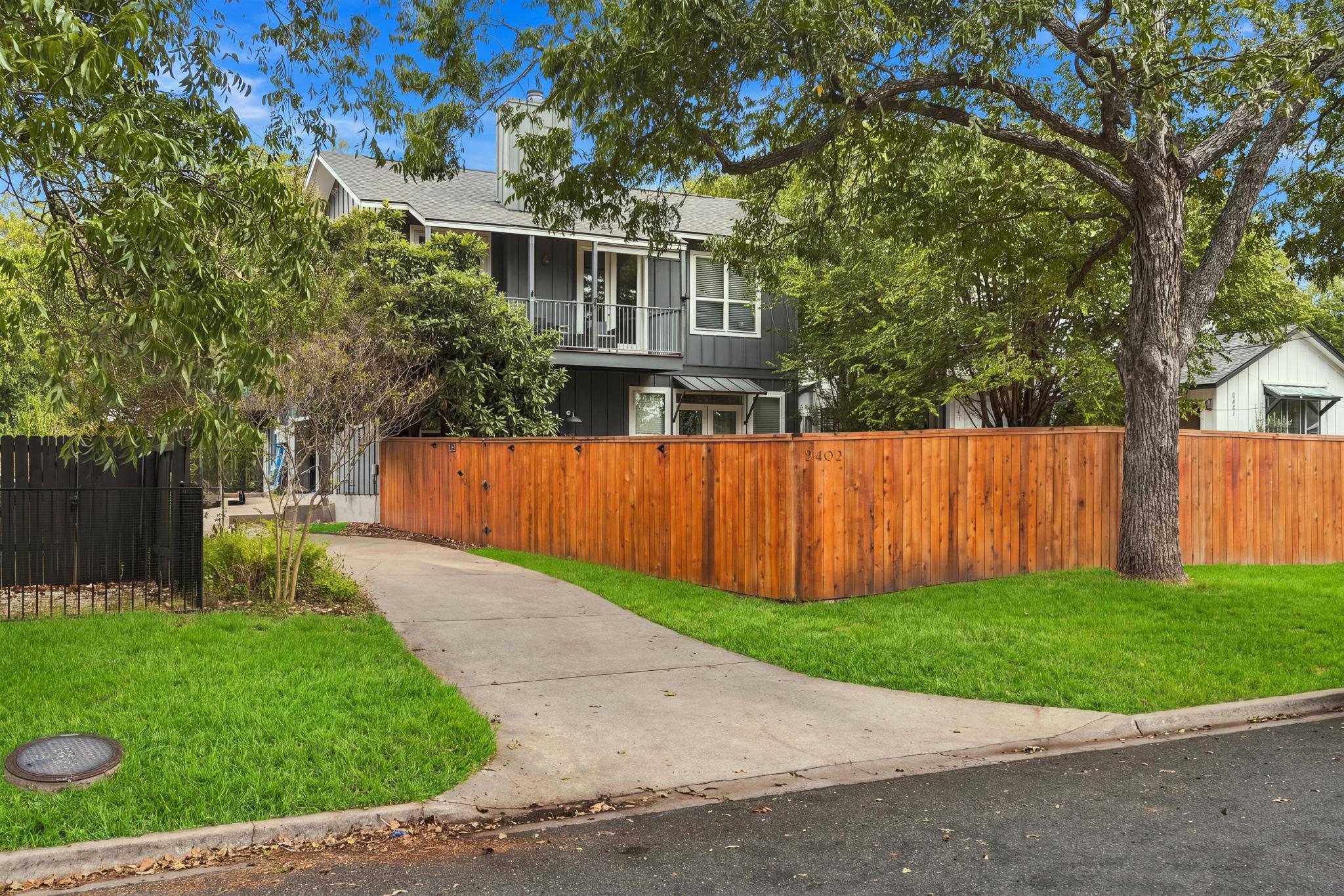 Mature trees shade a private fenced yard and a pa