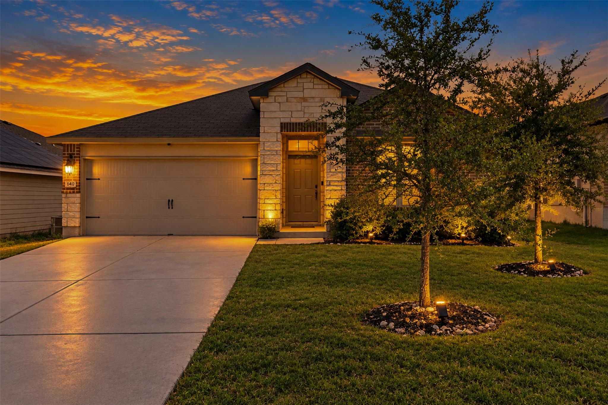 Dramatic sunset skies frame this modern stone-acc