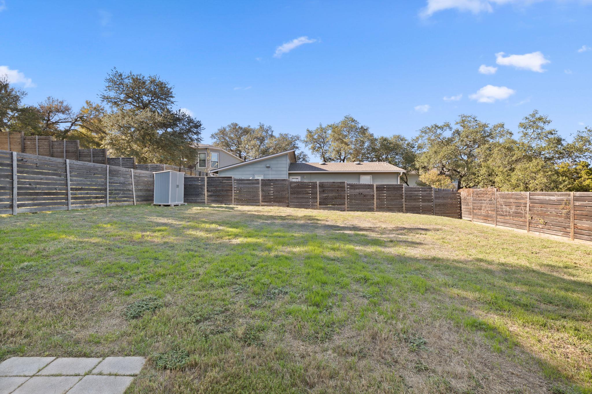 A spacious grassy lawn sits enclosed by privacy f