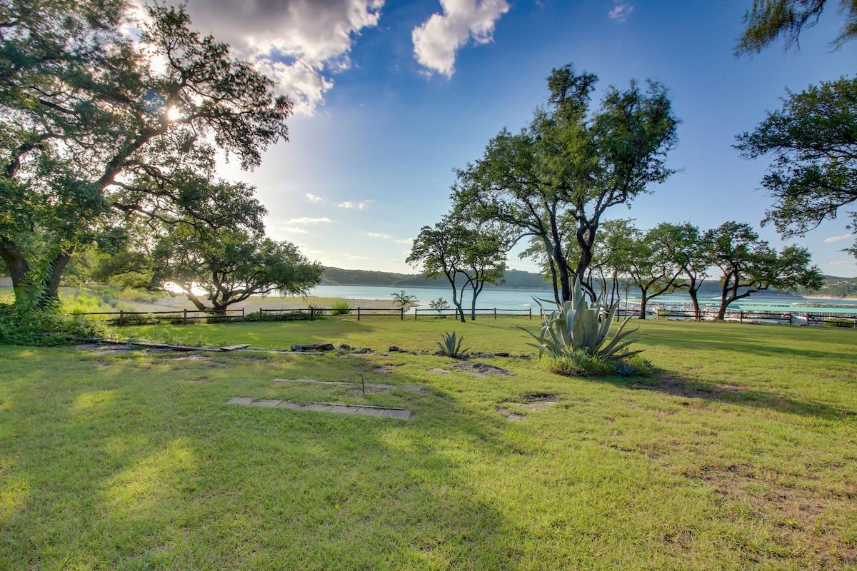 Mature trees shade a grassy lawn overlooking tran