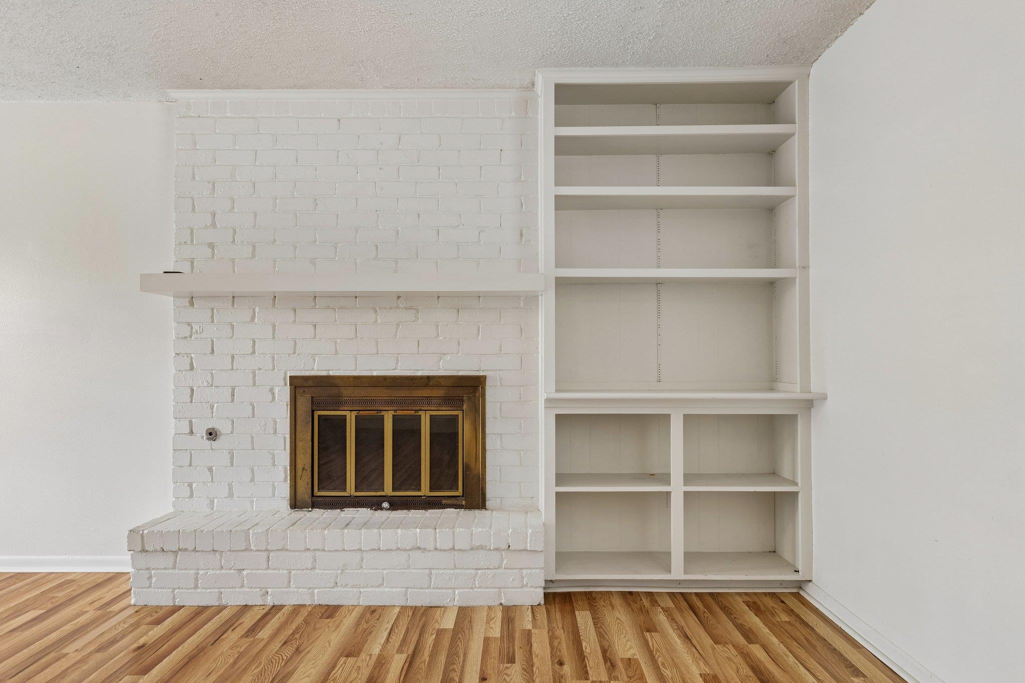 A brick fireplace with a mantel stands beside bui
