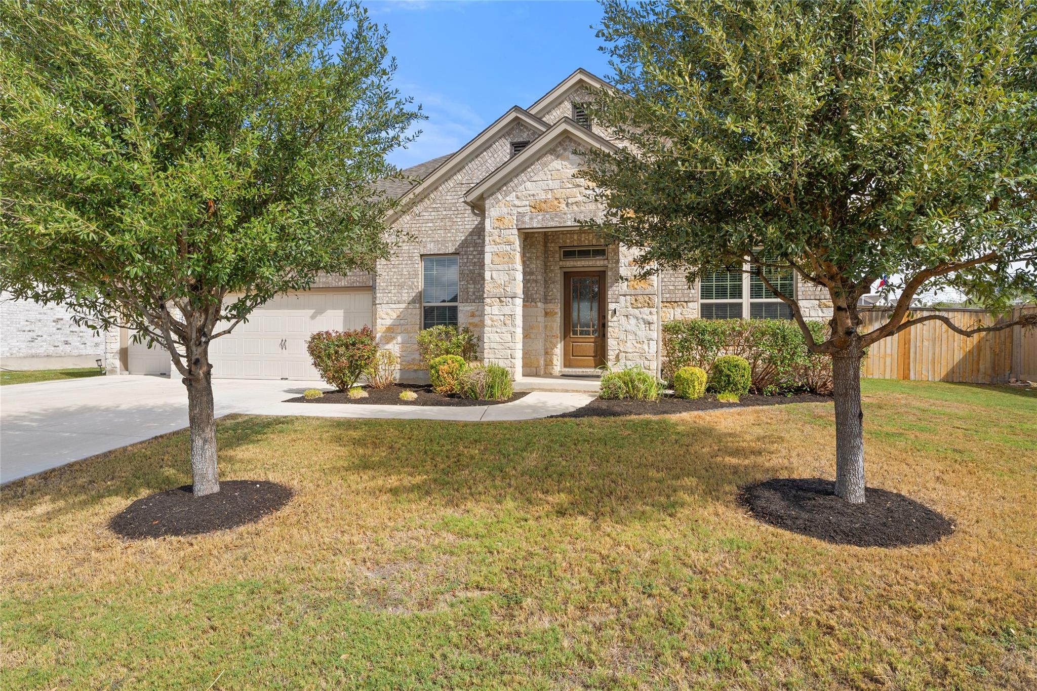 Mature trees frame a classic stone and brick faca