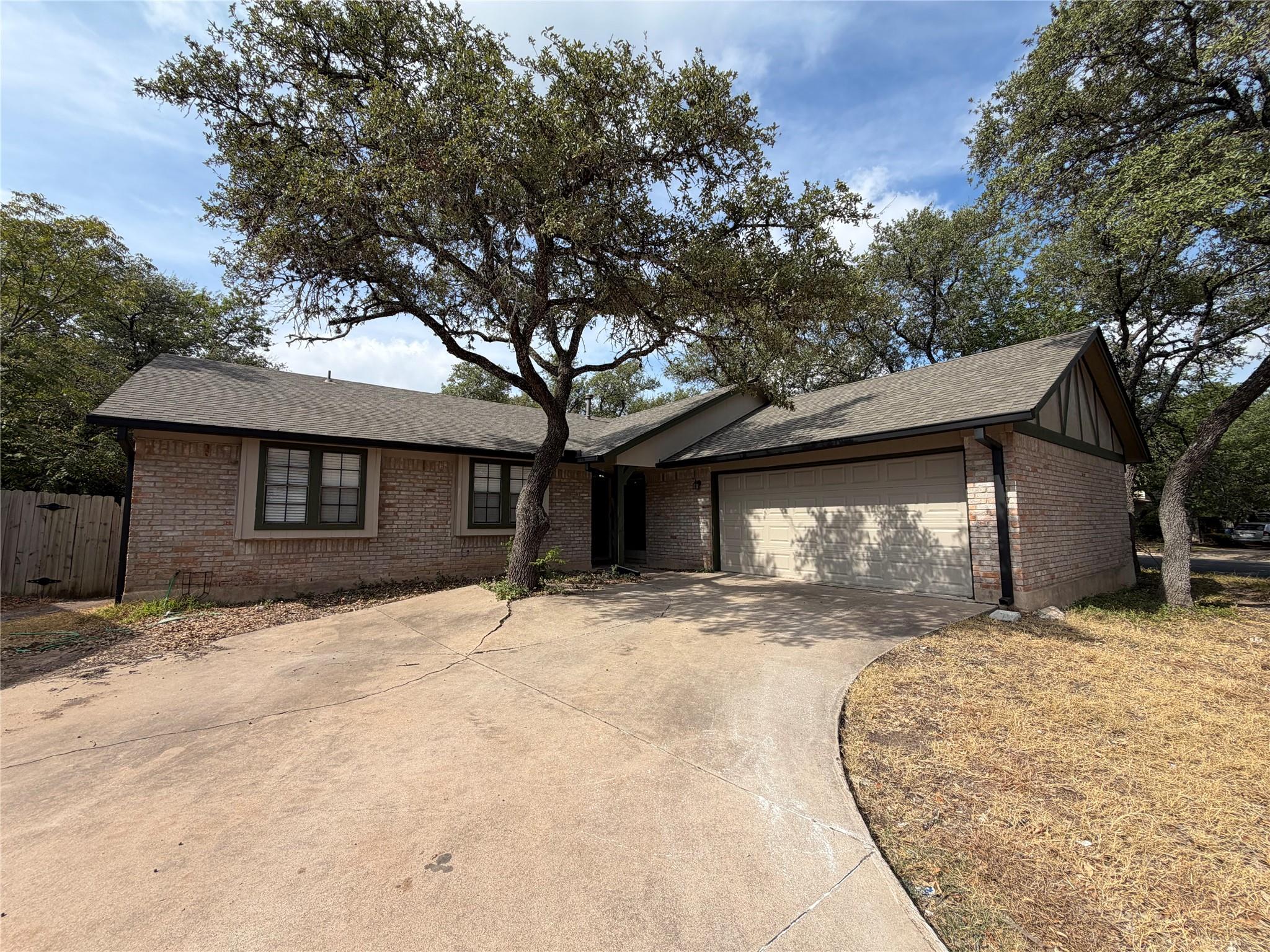 Mature oak trees frame this classic brick single-