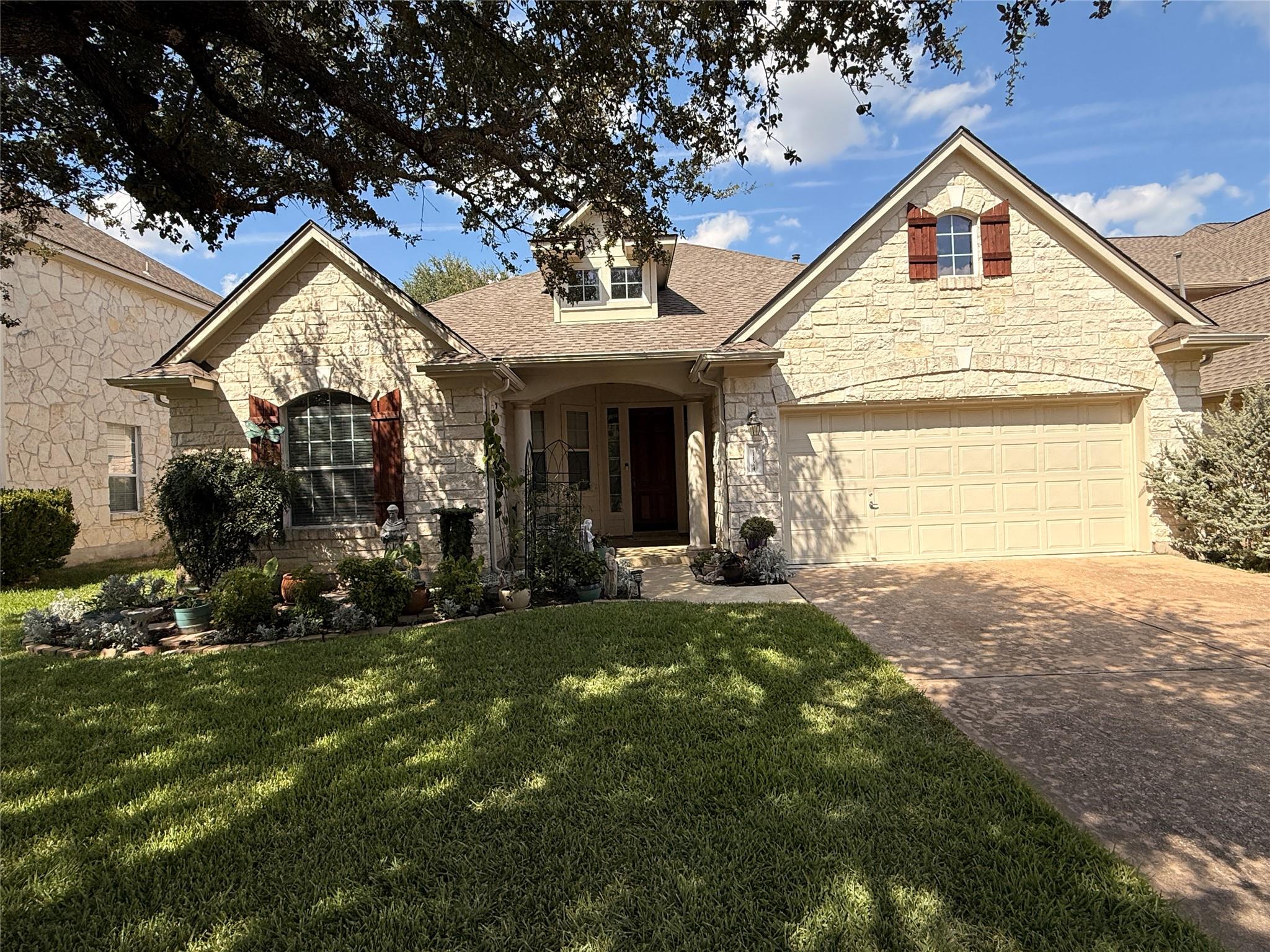Textured stone siding and a manicured lawn create