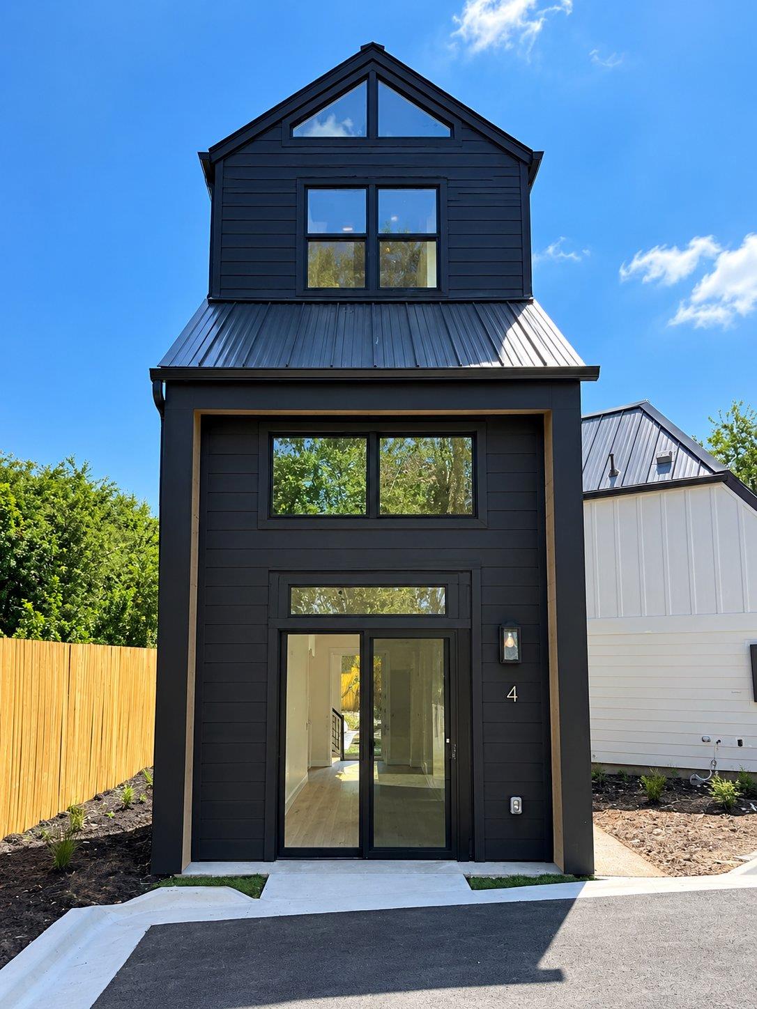 A striking modern facade pairs dark wood siding w