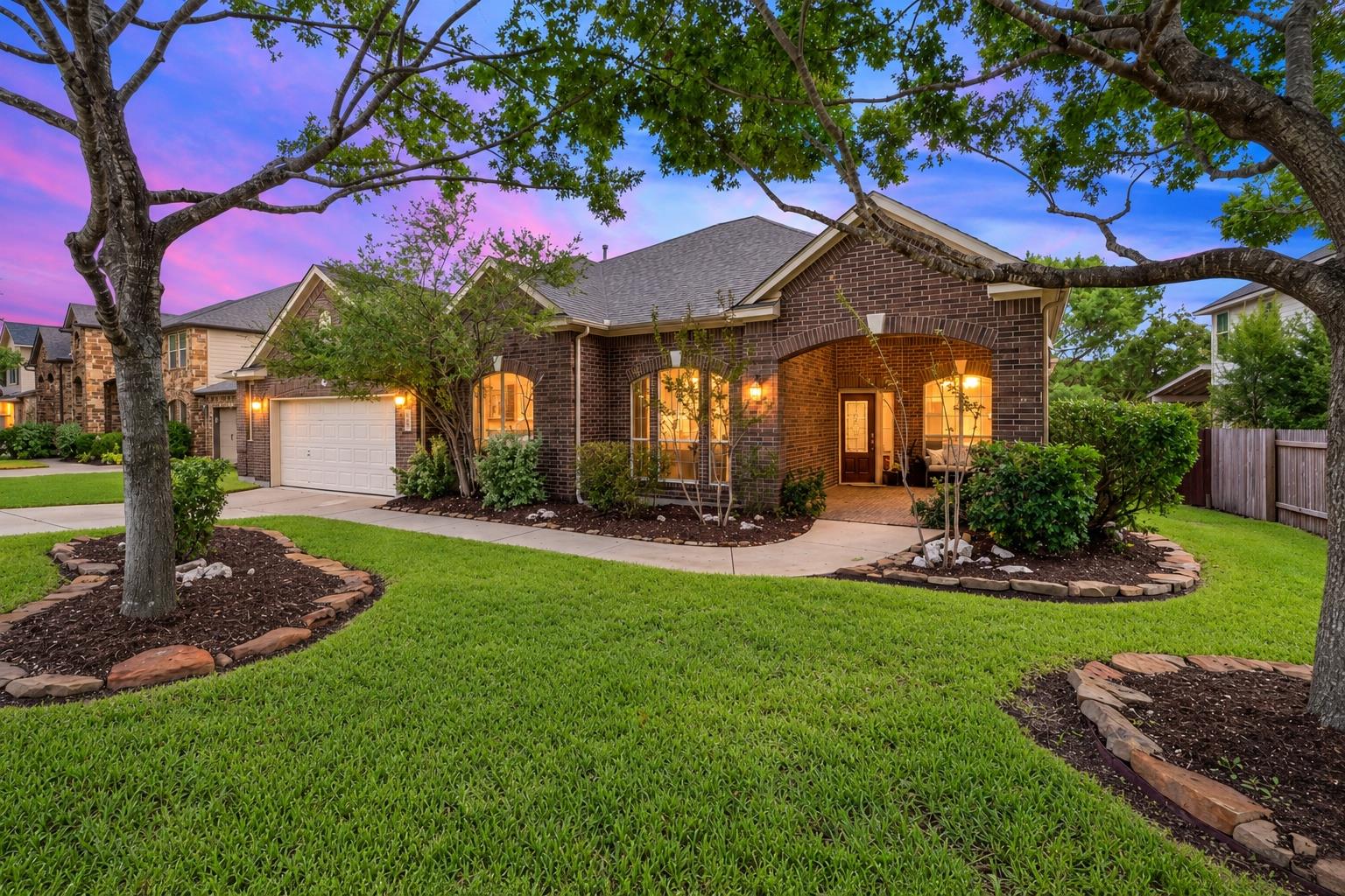 Mature trees shade a manicured front lawn leading
