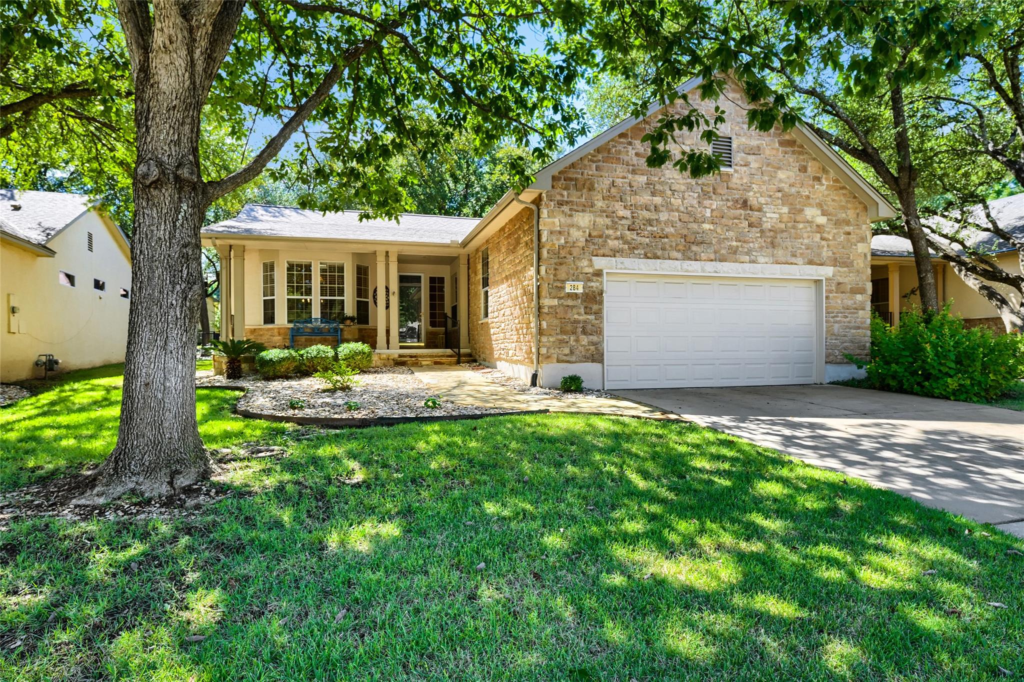Mature trees shade the stone facade and paved dri