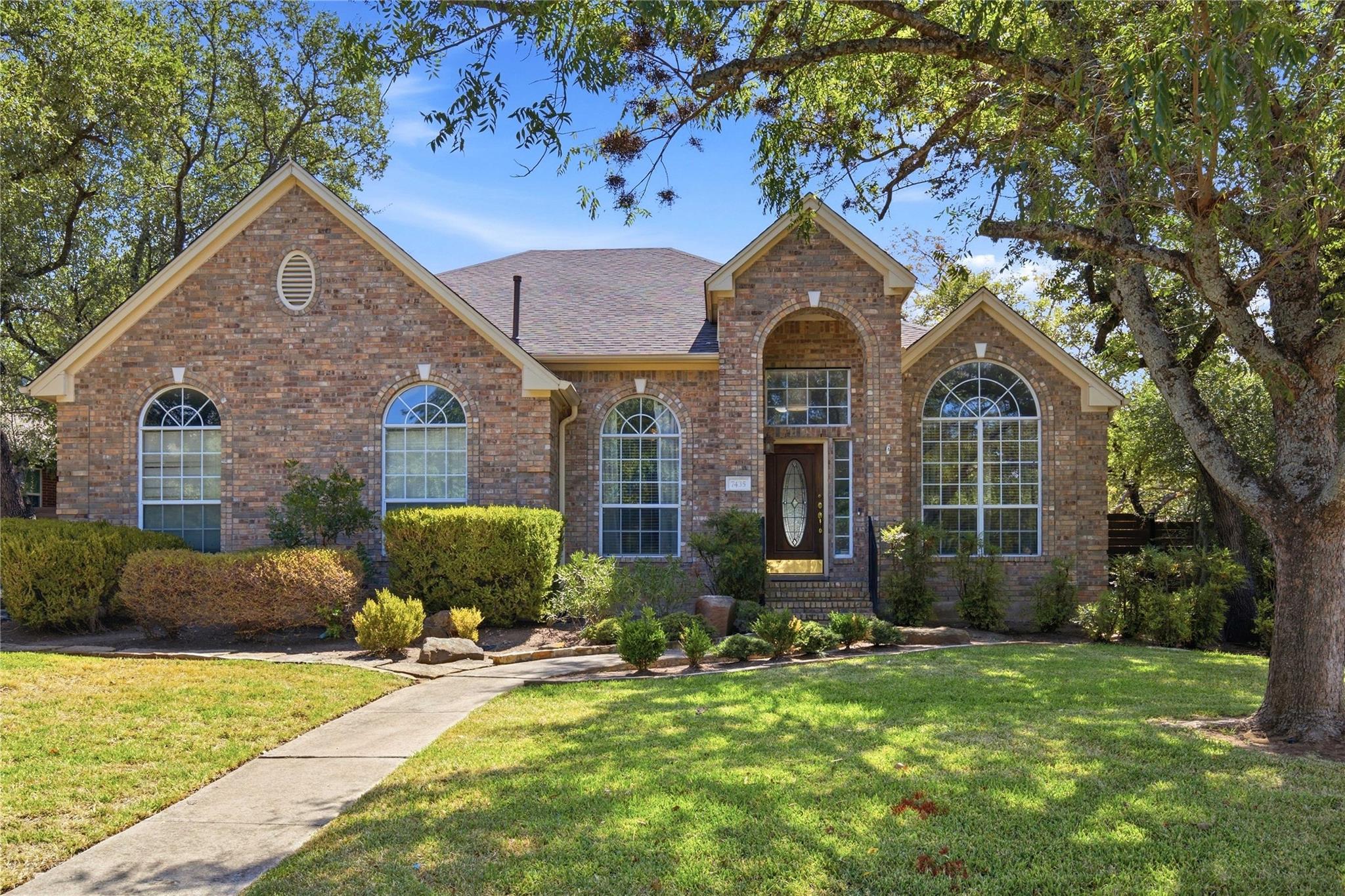 Mature trees shade a classic brick facade detaile
