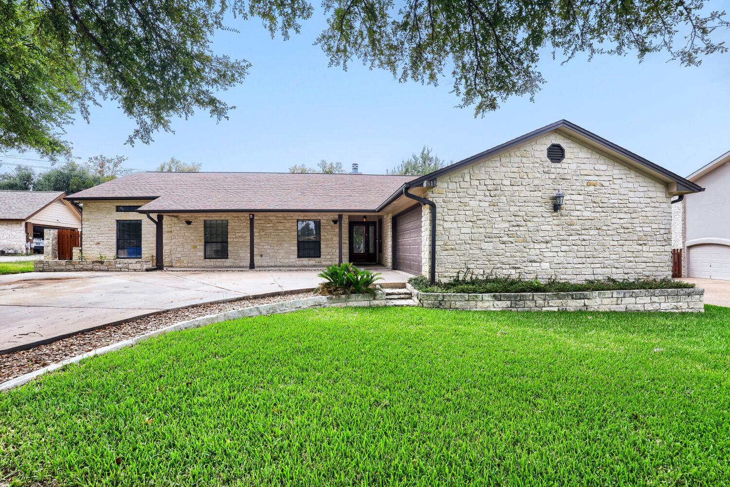 Textured stone siding and a wide driveway define 