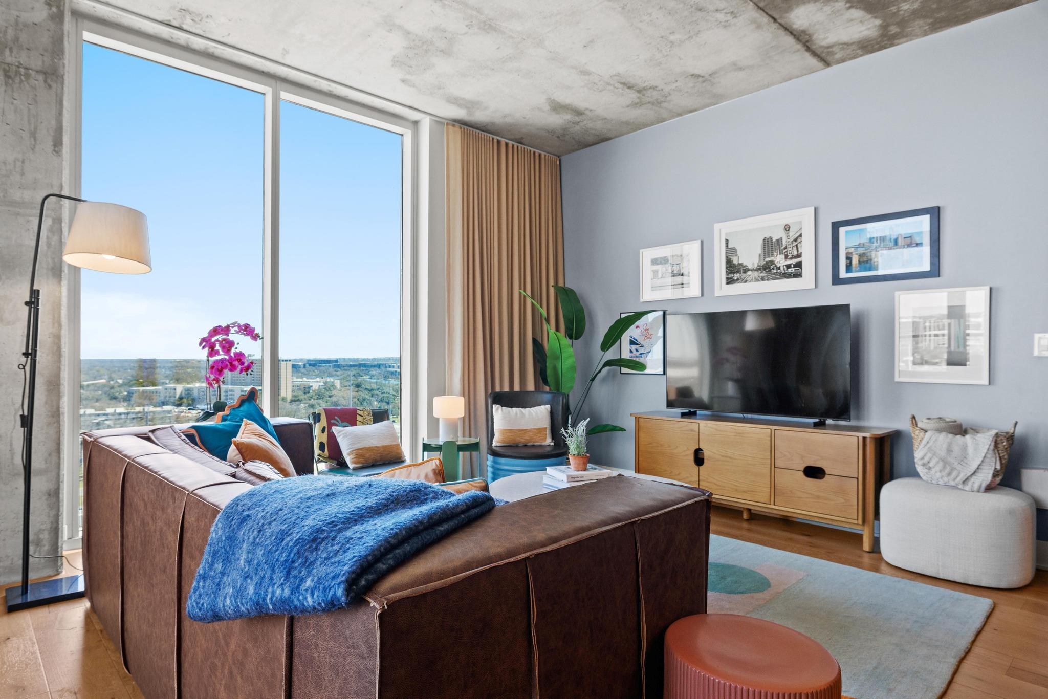 Floor-to-ceiling windows flood this modern living