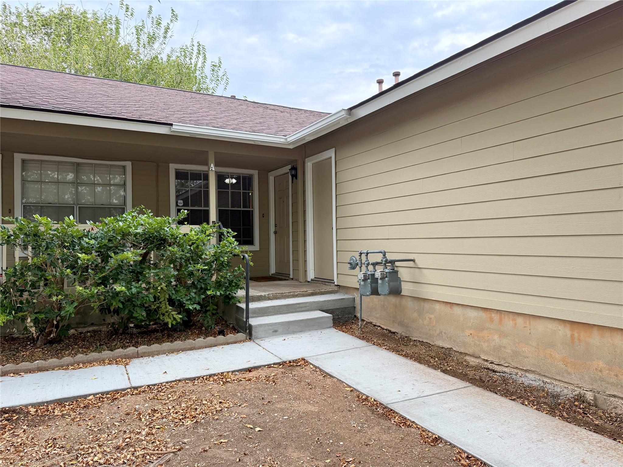 A neat concrete walkway leads to the entrance of 