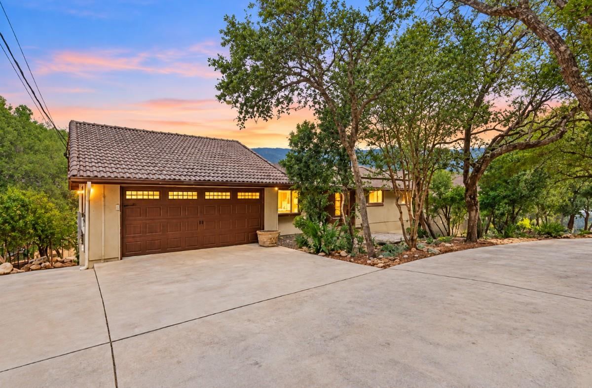 Mature trees frame the concrete driveway leading 