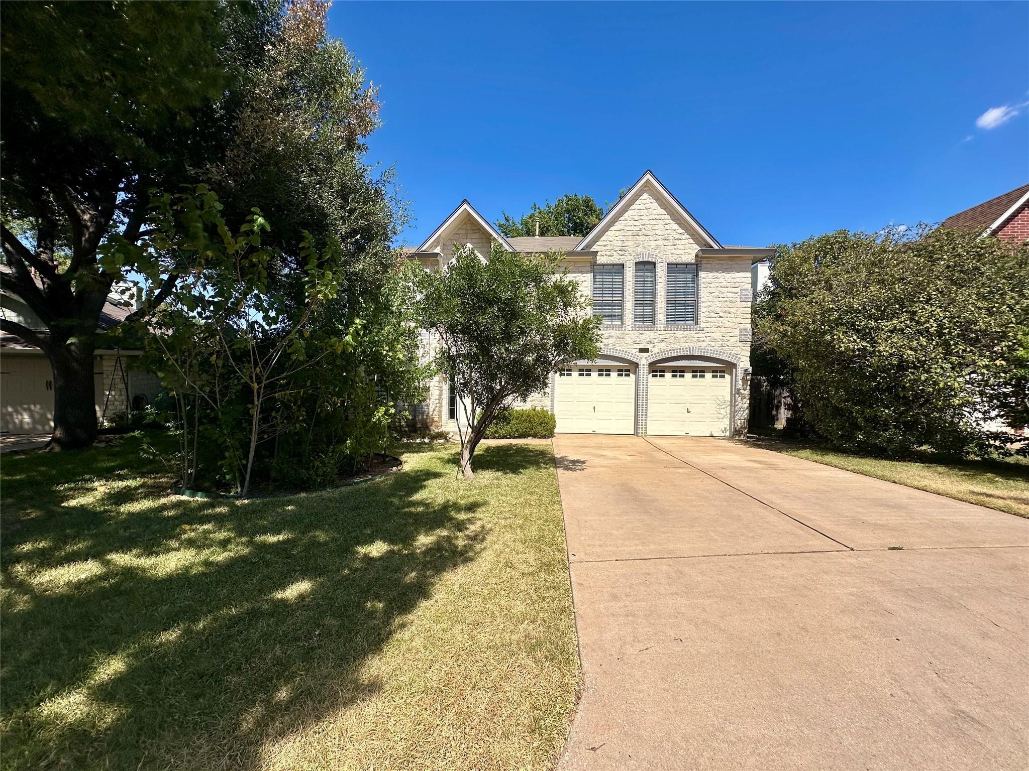 A long concrete driveway leads to a stone facade 