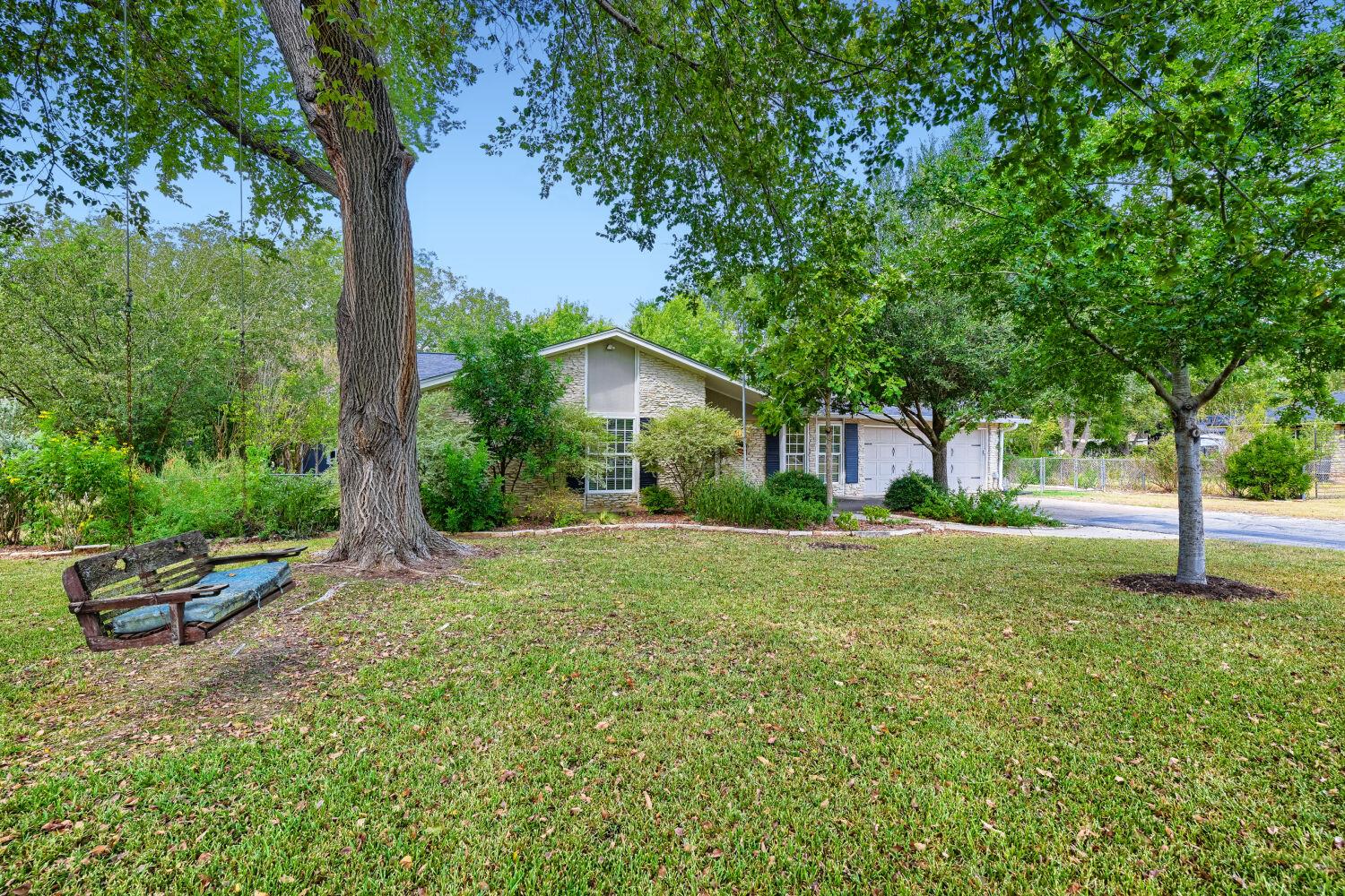 Mature trees shade a spacious green lawn leading 