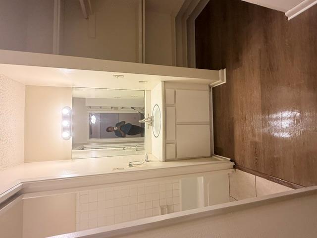 Rich wood flooring runs past the vanity area lead