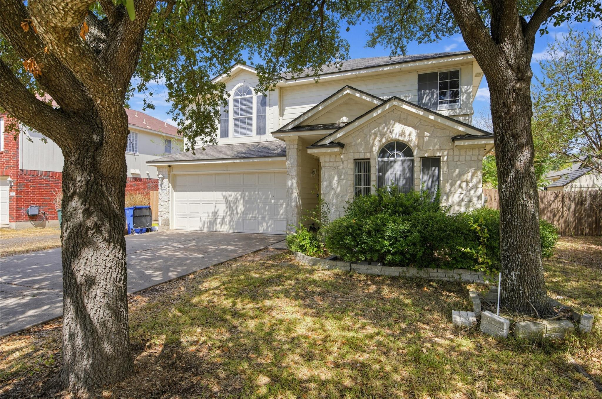 Mature trees frame the stone-accented facade and 