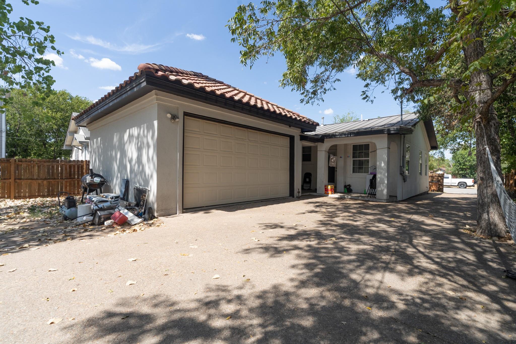 Mature trees shade the driveway leading to a two-