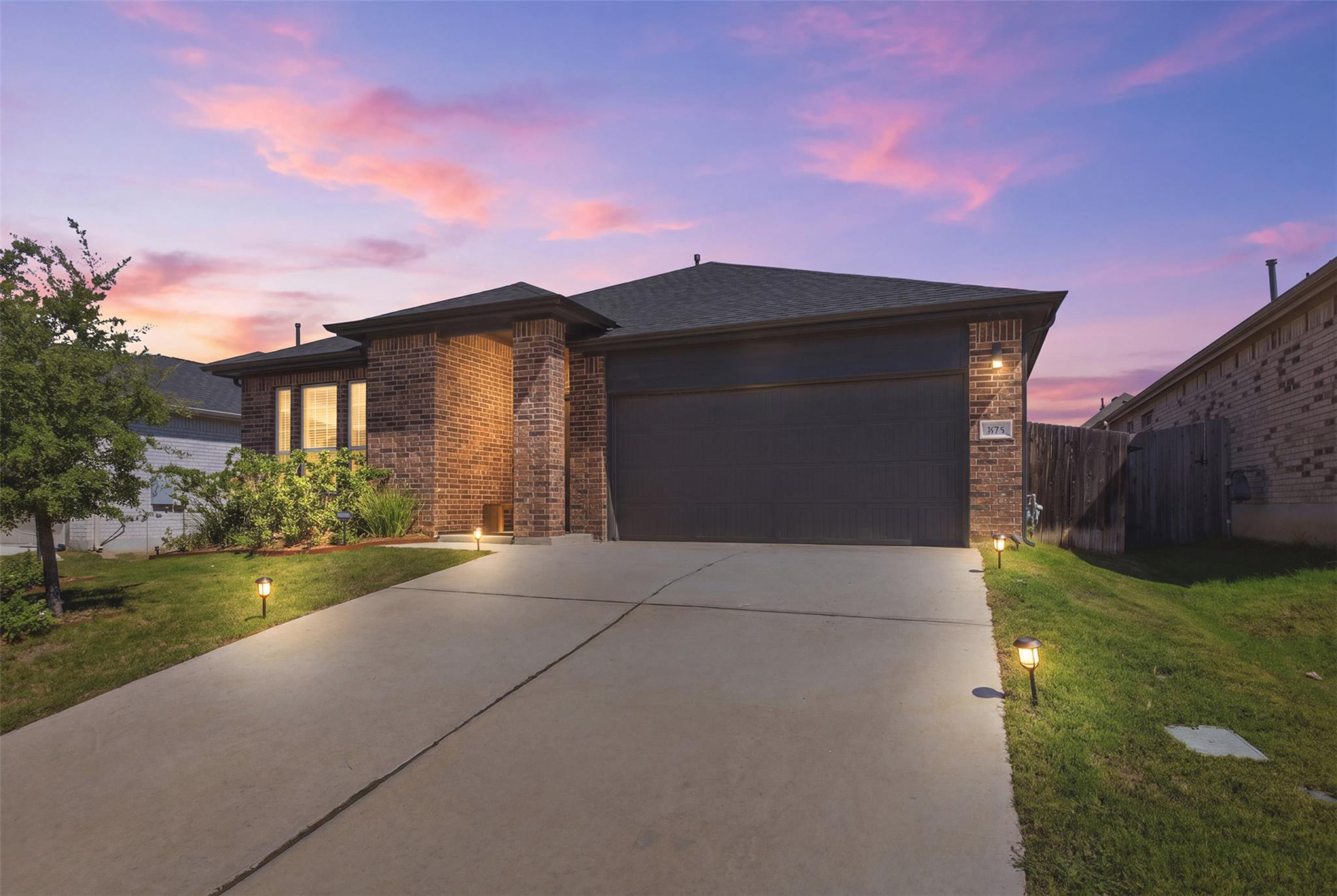 Brick siding and a wide concrete driveway define 
