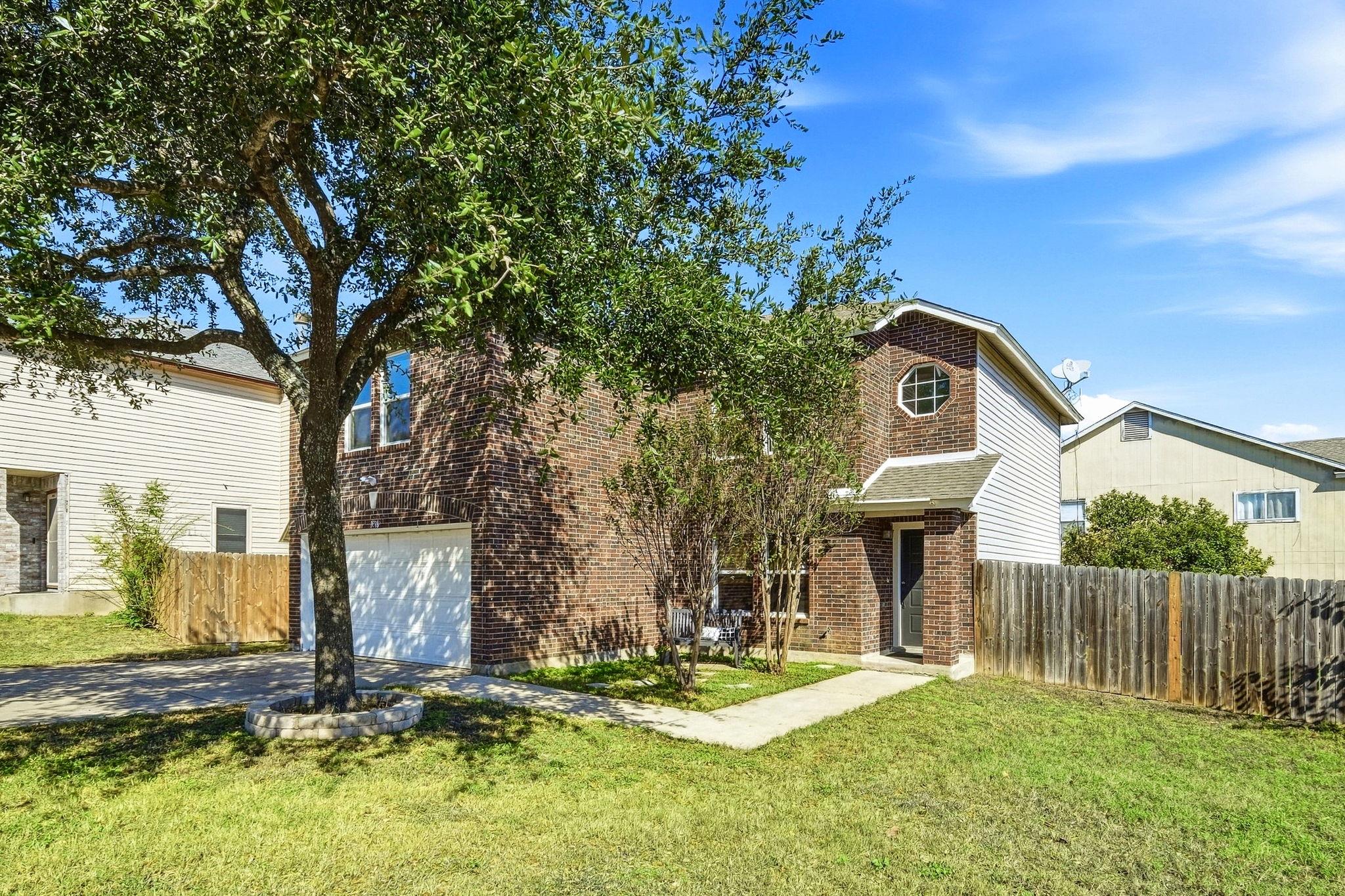 Mature trees frame a classic brick exterior compl