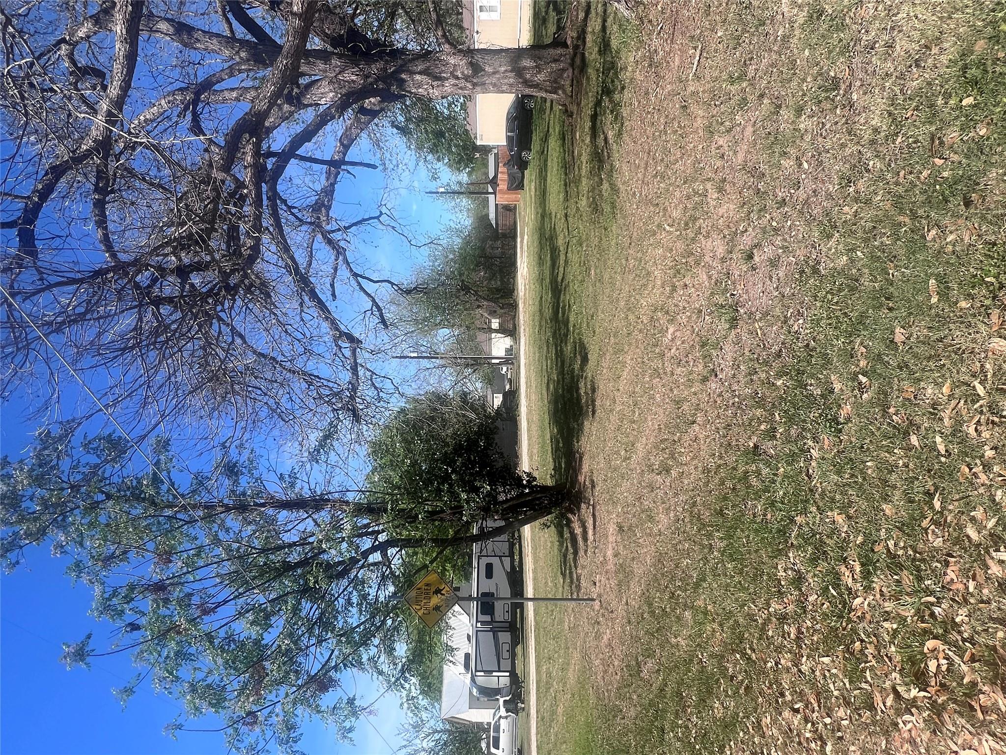 Mature trees shade a spacious grassy yard under c
