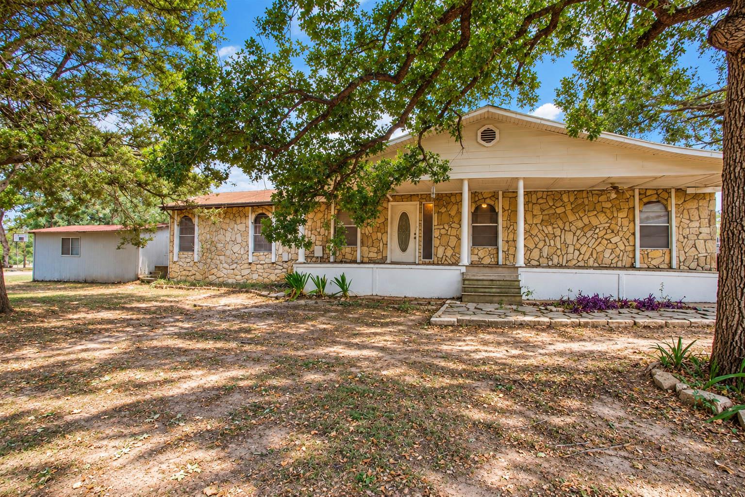 Mature shade trees frame a classic stone exterior