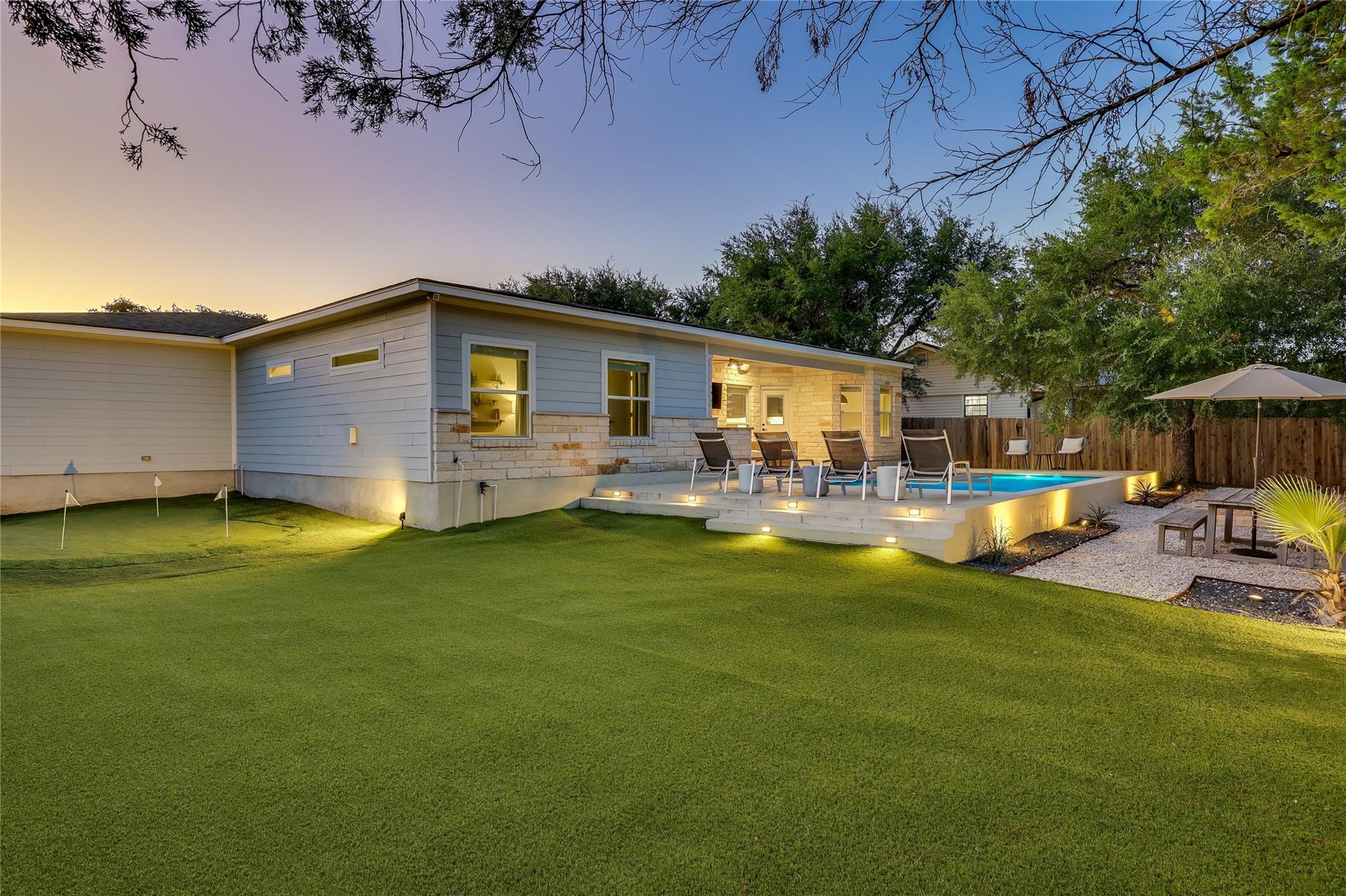 A well-manicured lawn surrounds a stone-accented 