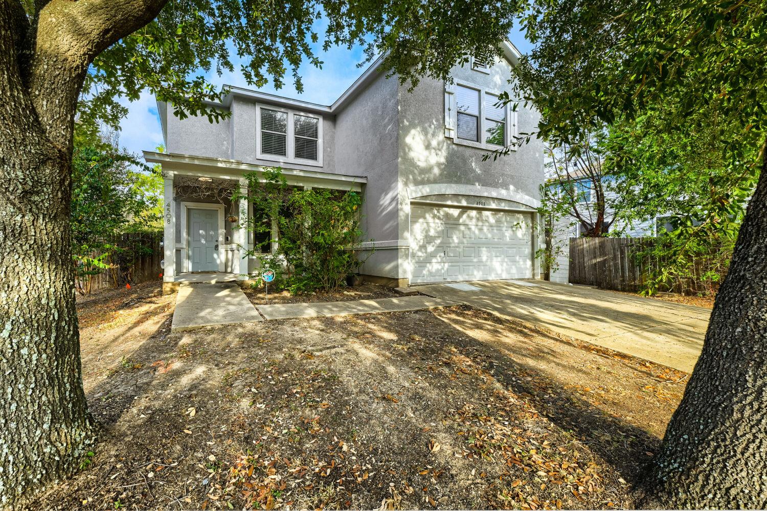 Mature trees frame the stucco exterior of this tw