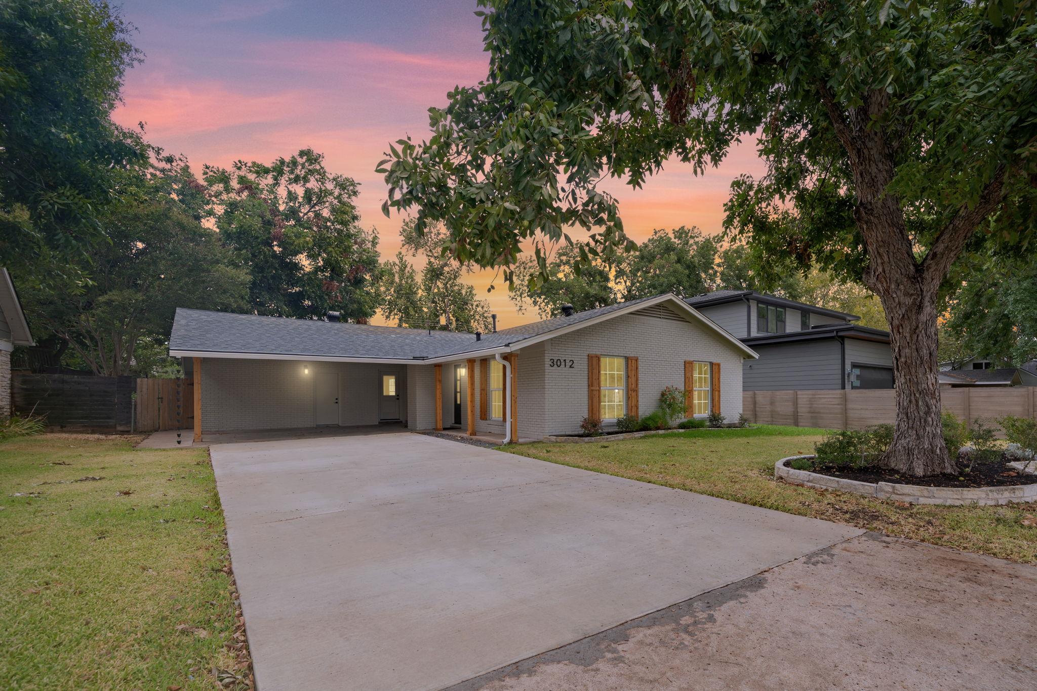 A wide concrete driveway leads toward this classi