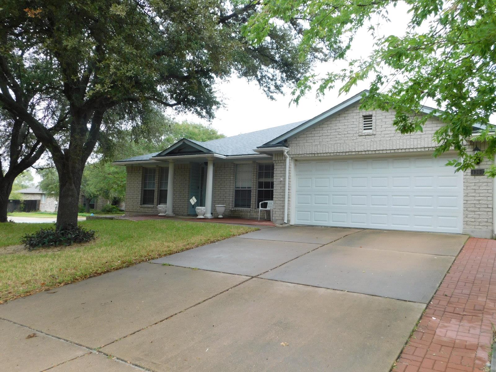 Mature trees shade the brick exterior and wide dr