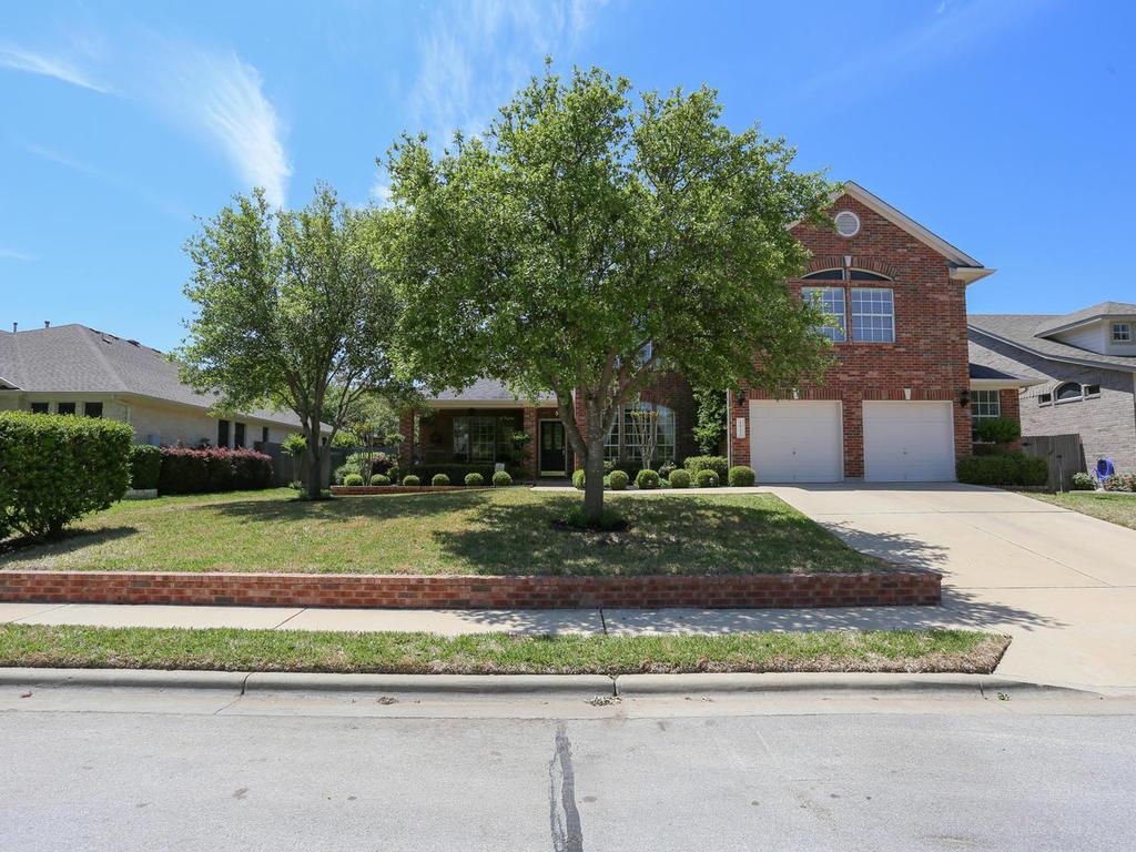Mature shade trees and brick accents frame this c