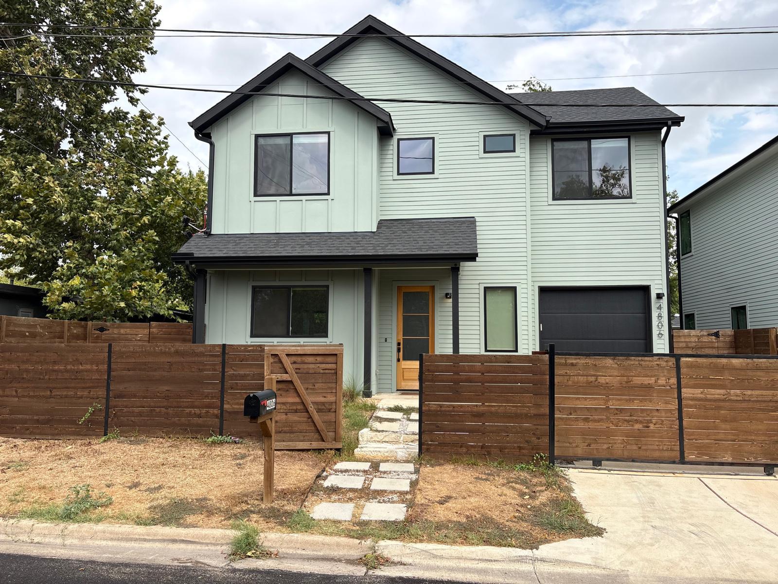 A fenced front yard leads to this modern two-stor