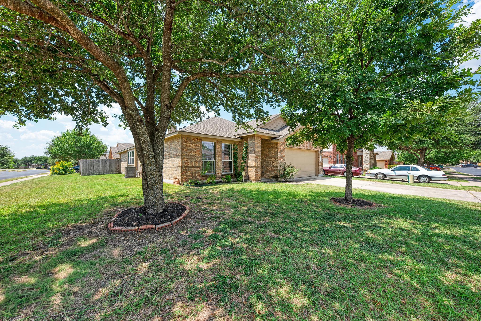 Mature shade trees frame the classic brick facade