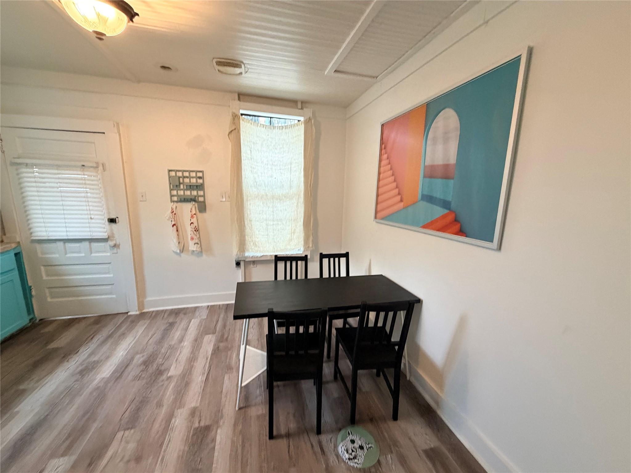 A casual dining space features wood-patterned flo