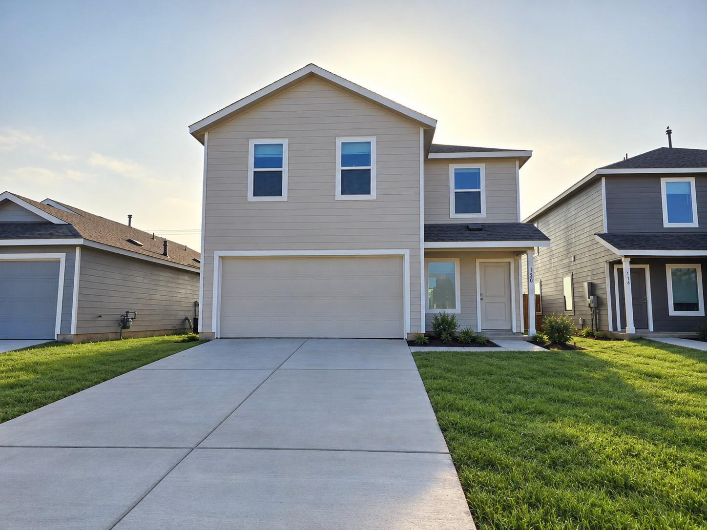 A wide concrete driveway leads toward the two-car