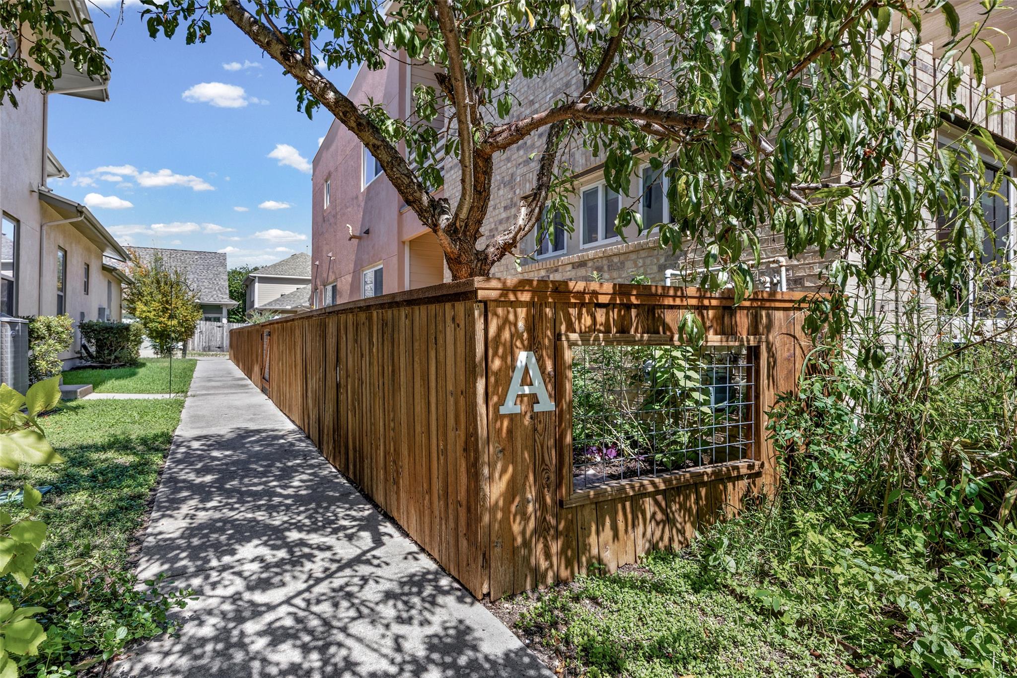 A concrete walkway runs alongside a wooden fence 