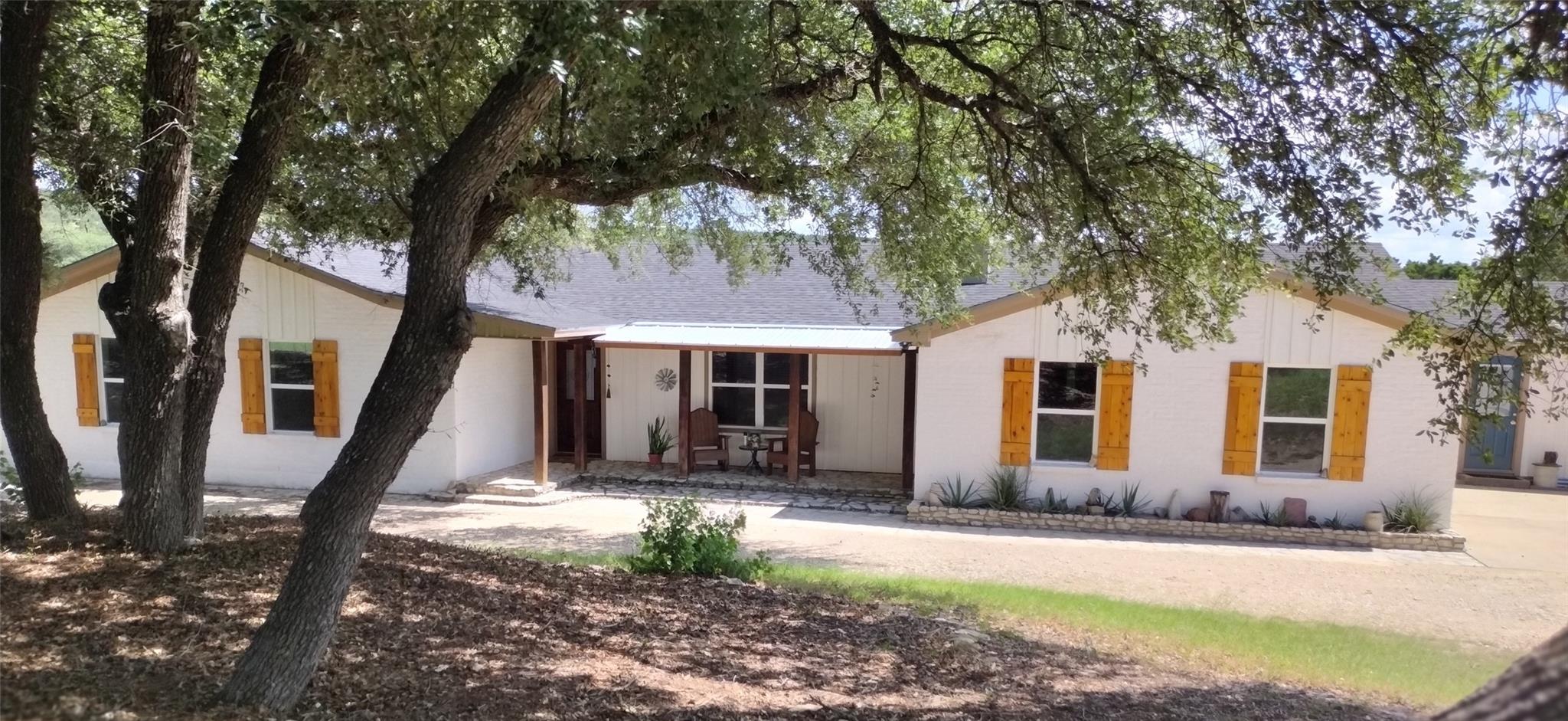 Mature oak trees shade a welcoming ranch-style ho