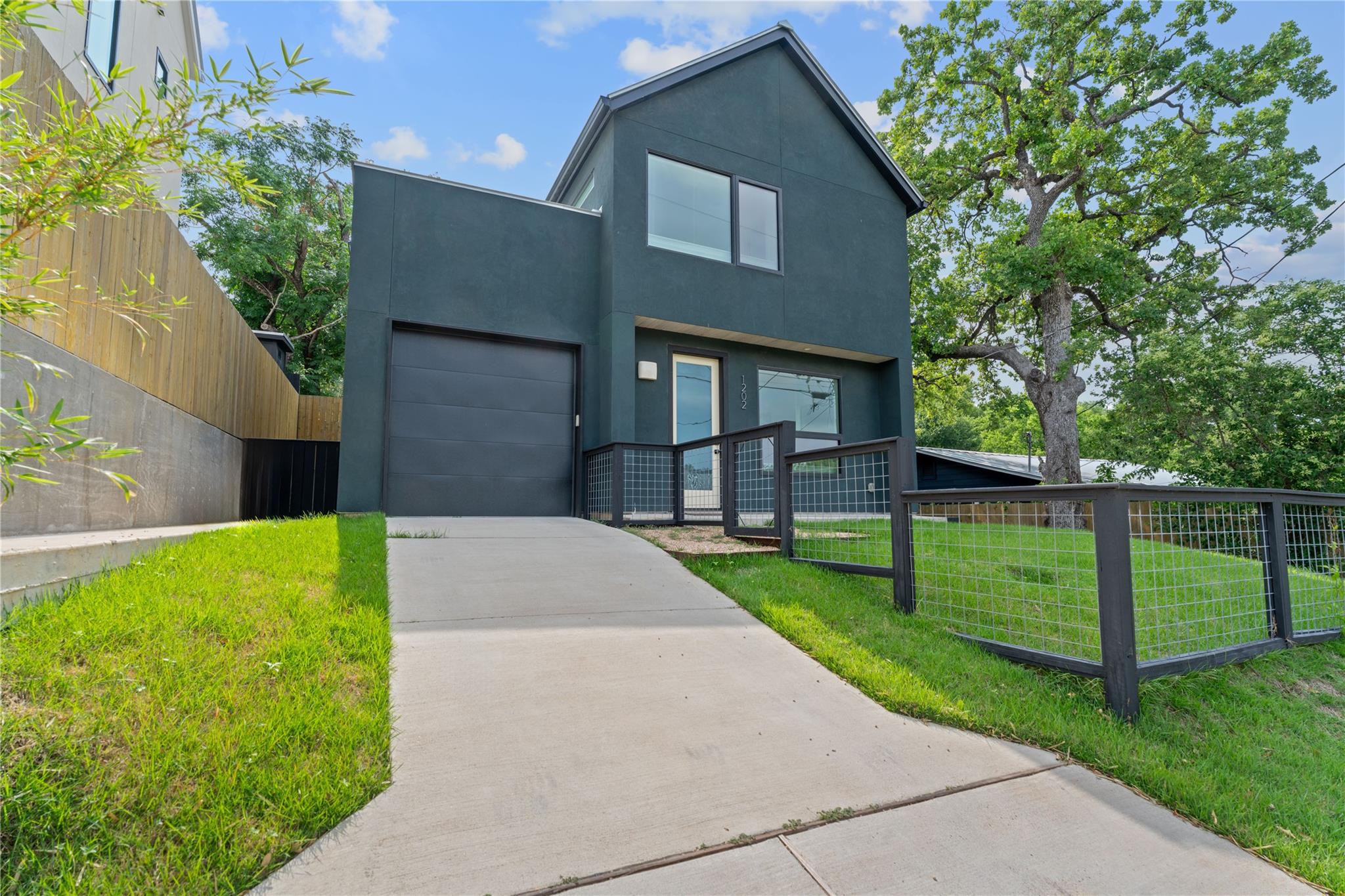 A concrete driveway leads to this modern home wit