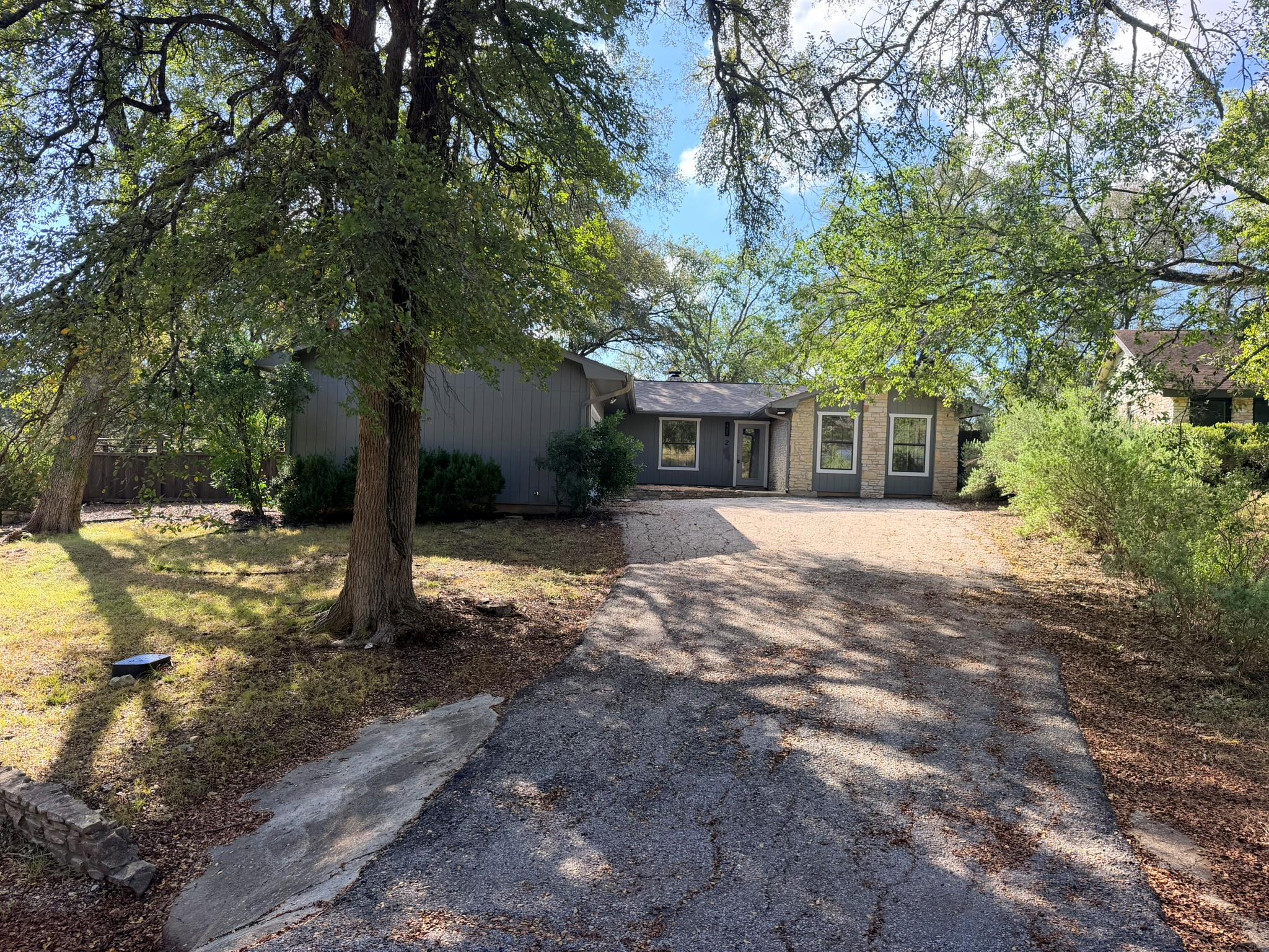 Mature trees shade the driveway leading to a priv