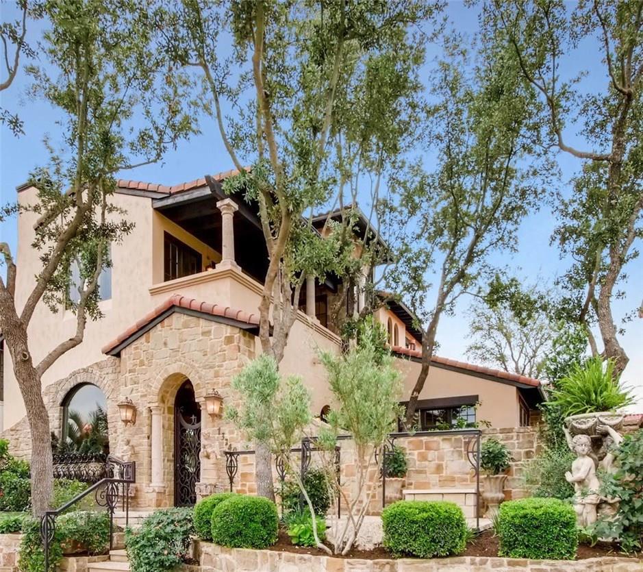 Mature trees frame a Mediterranean-inspired stone