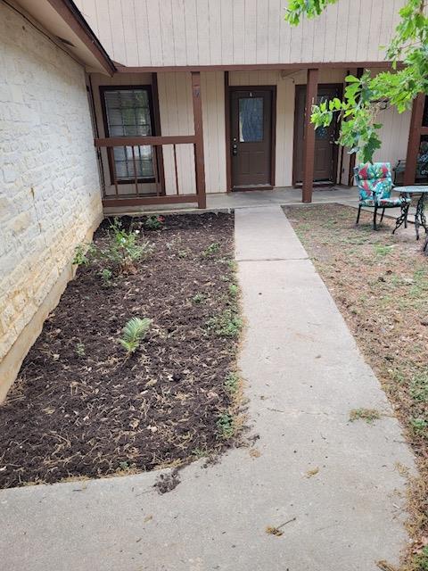 A concrete walkway leads past mulched garden beds