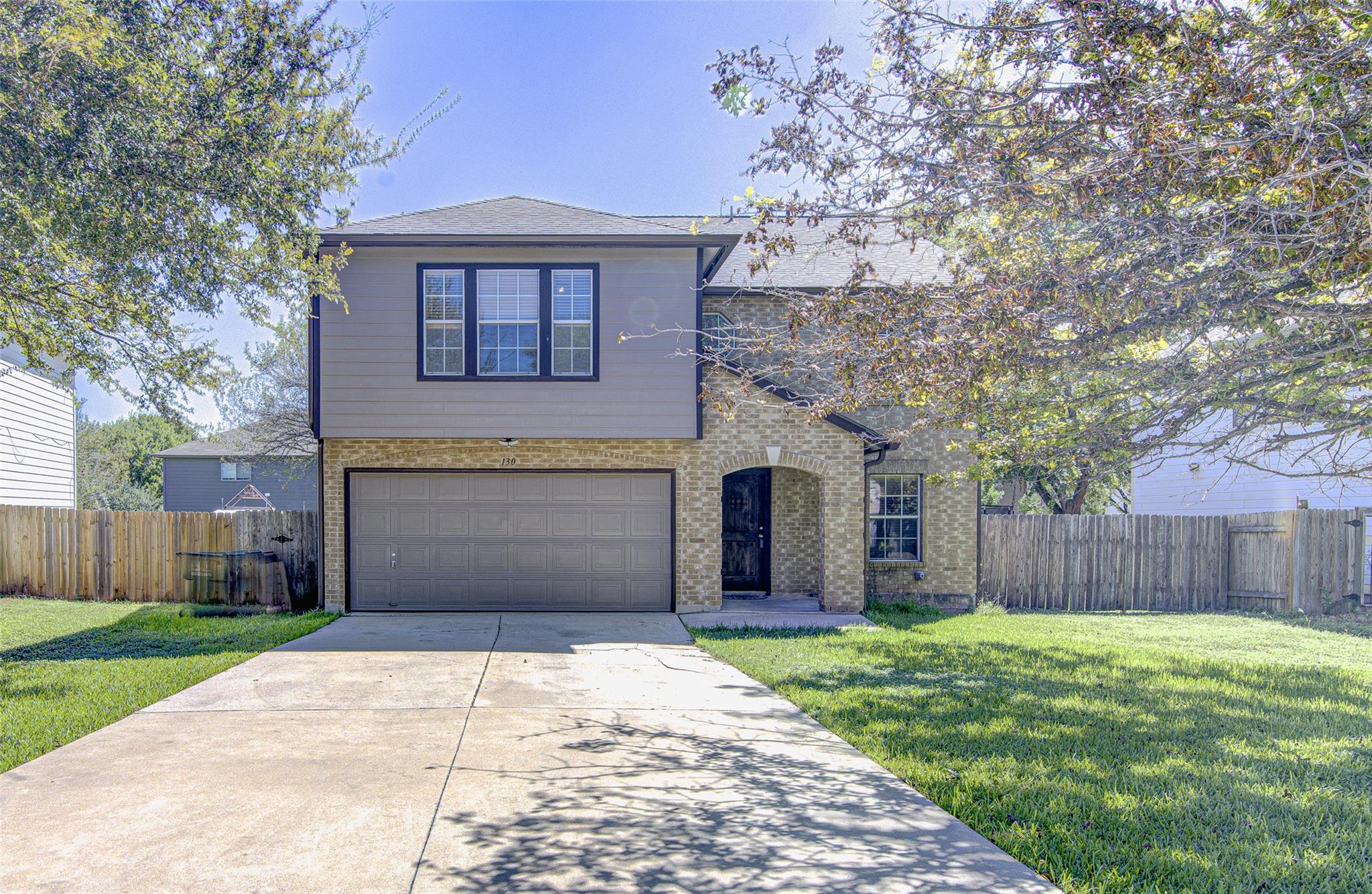Mature trees shade the front lawn and paved drive