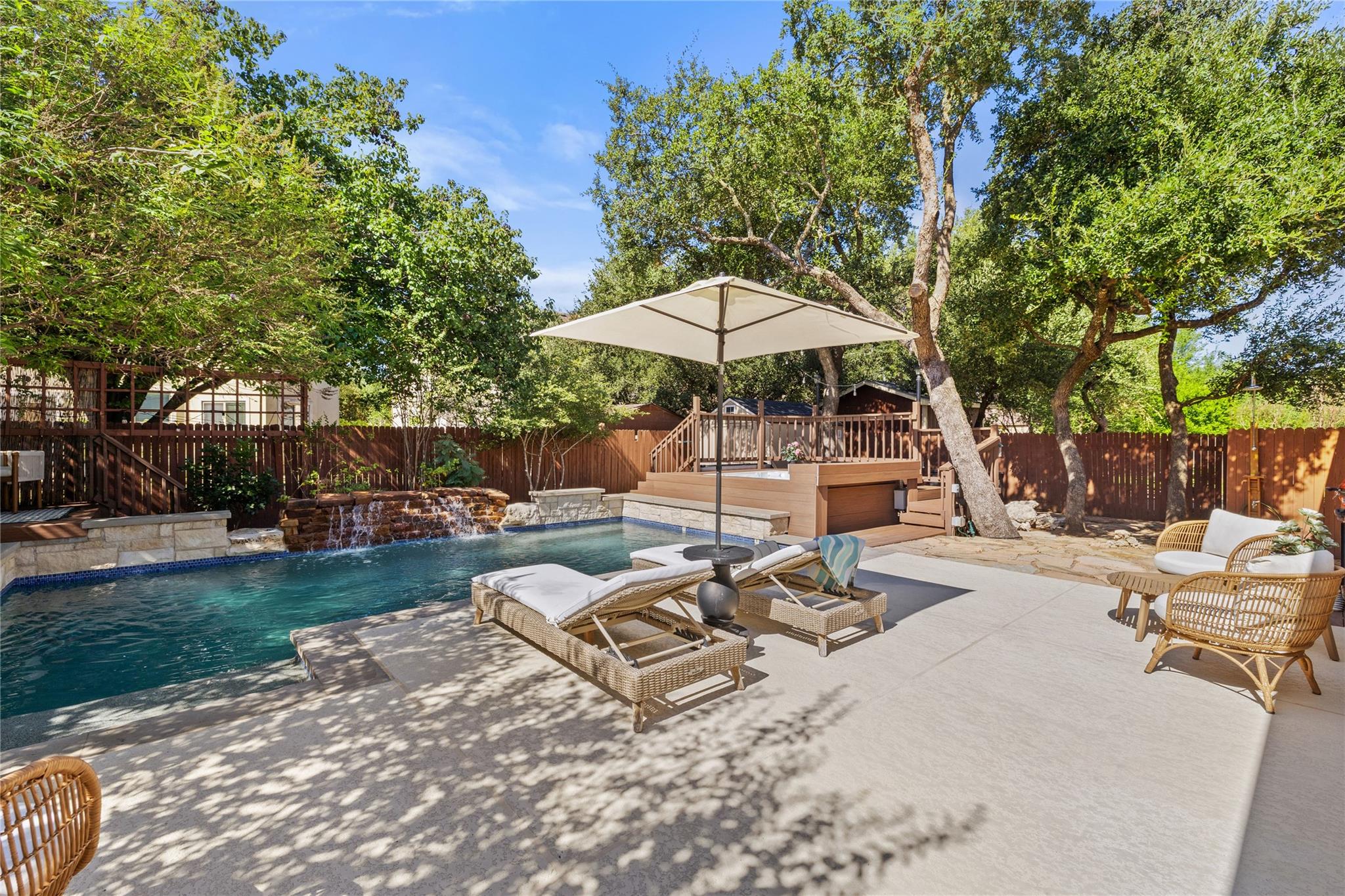 Mature trees frame a private backyard oasis featu