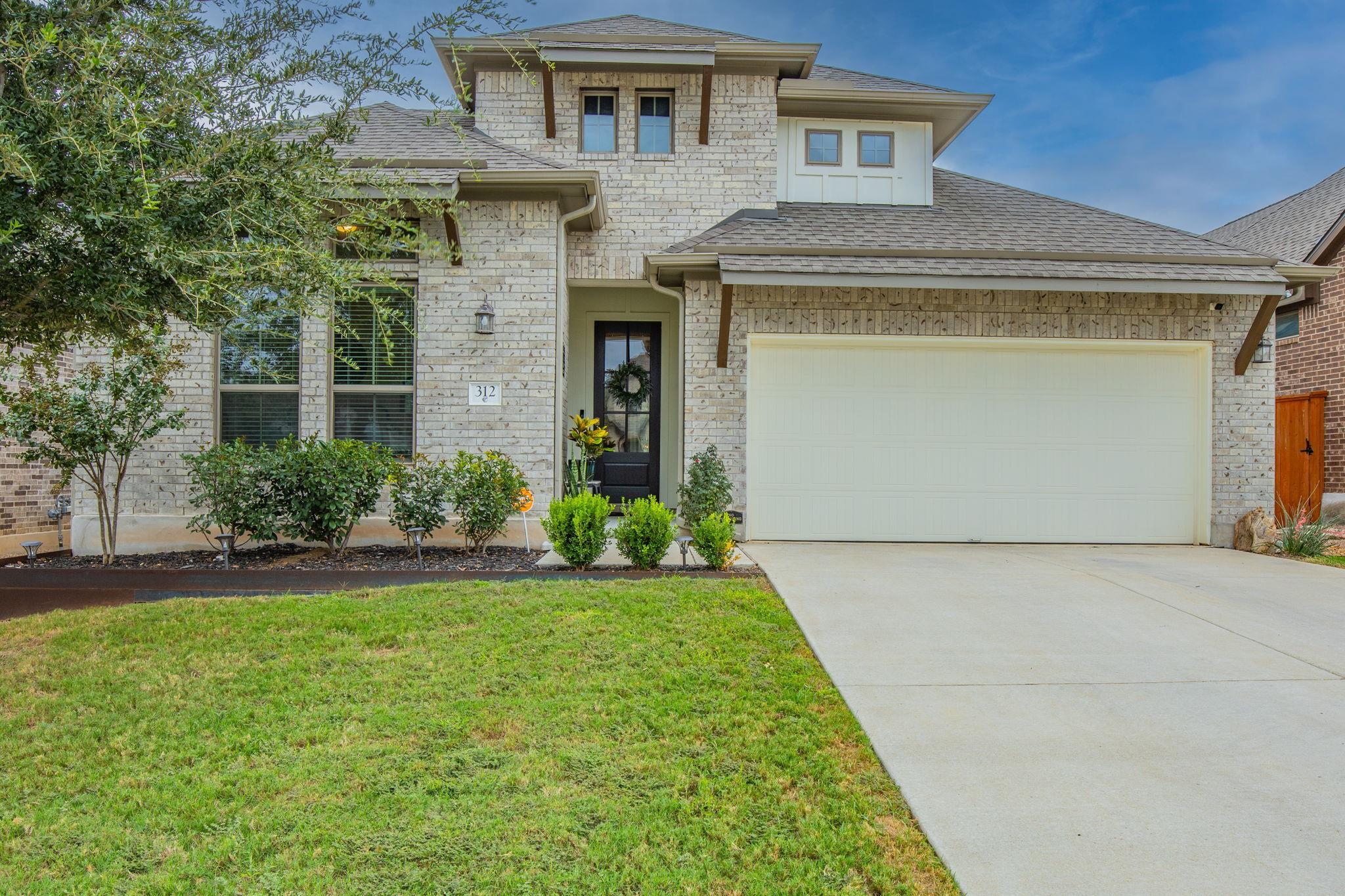 A spacious concrete driveway leads toward the two