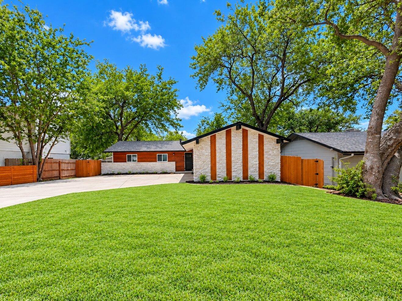 Mature trees frame a manicured green lawn leading